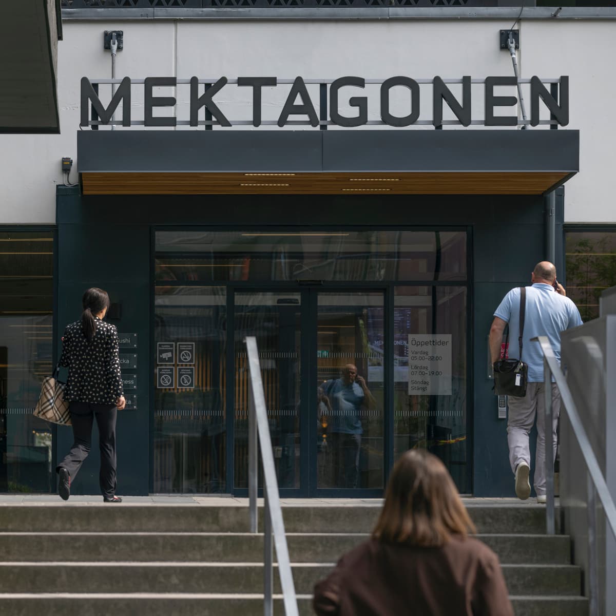 En kvinna går nerför en trappa framför en byggnad.