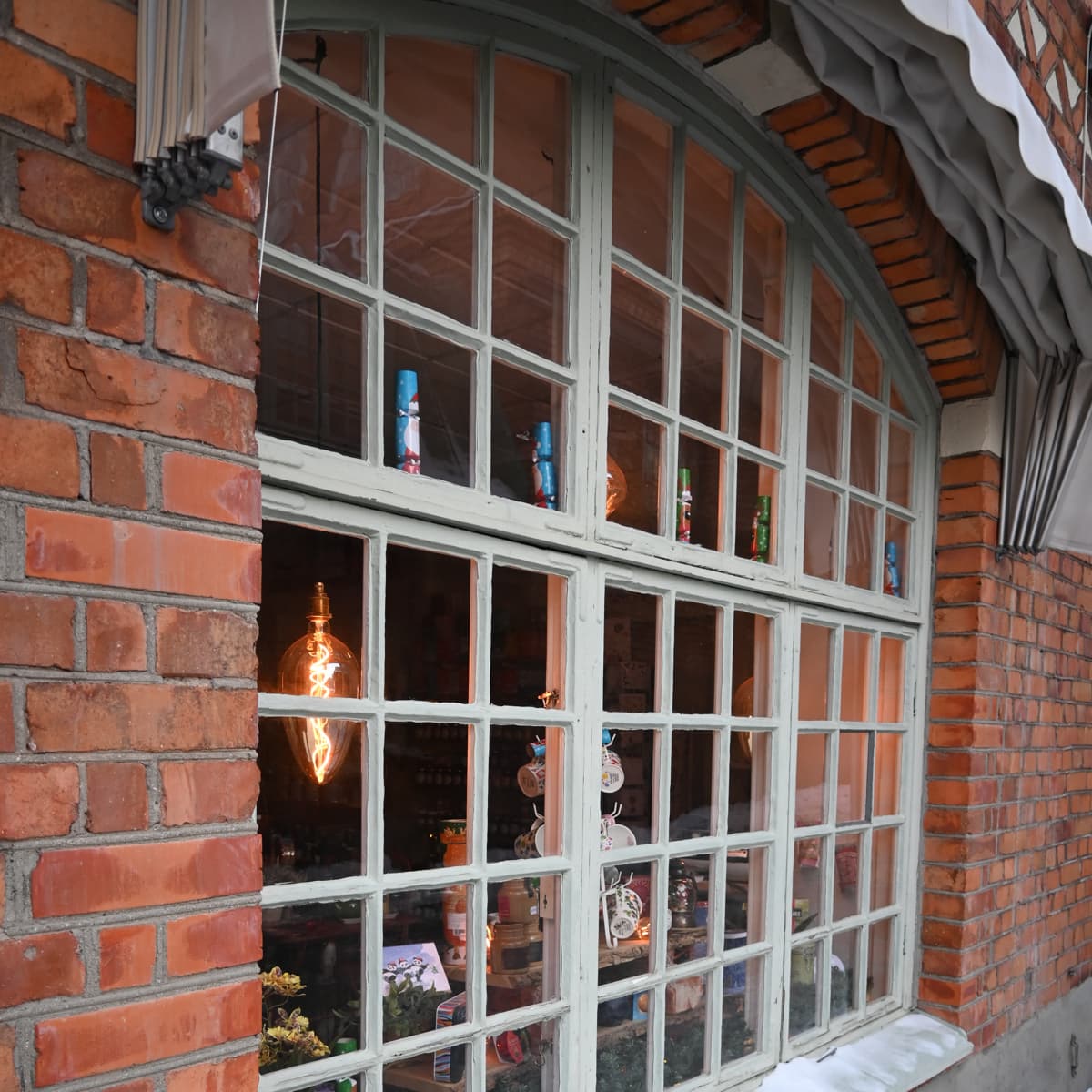 En tegelbyggnad med ett fönster och en glödlampa i fönstret.