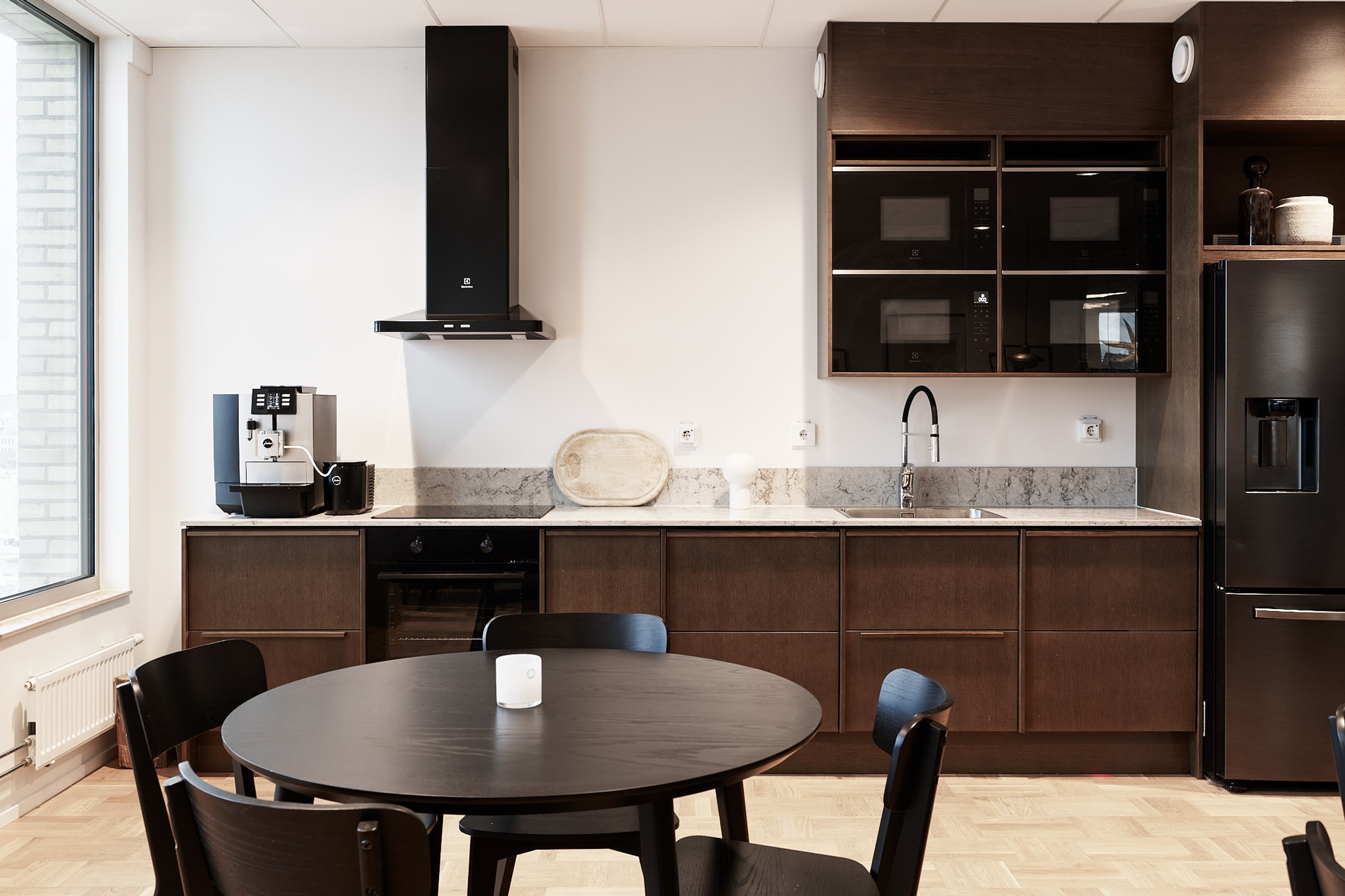 Ett kök med bord, stolar och kylskåp.