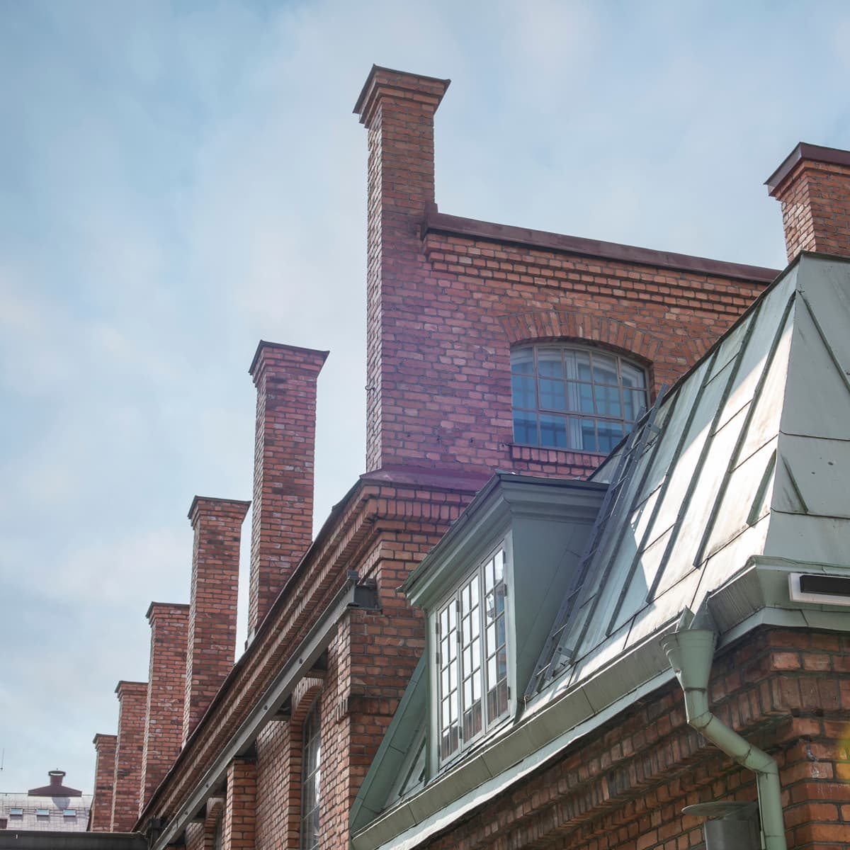 En tegelbyggnad med tak och fönster av metall.