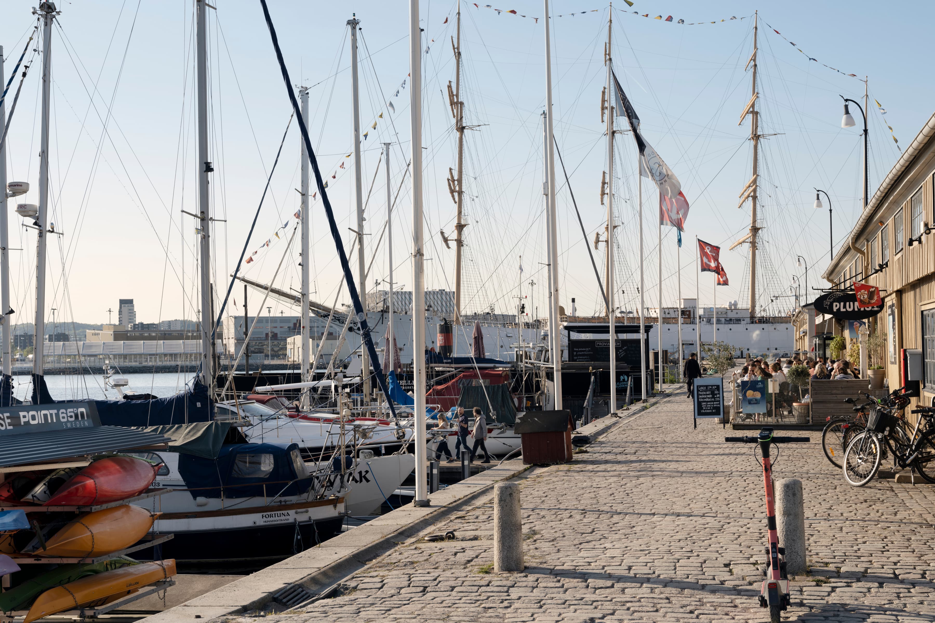 En rad segelbåtar som ligger bredvid varandra i en hamn.