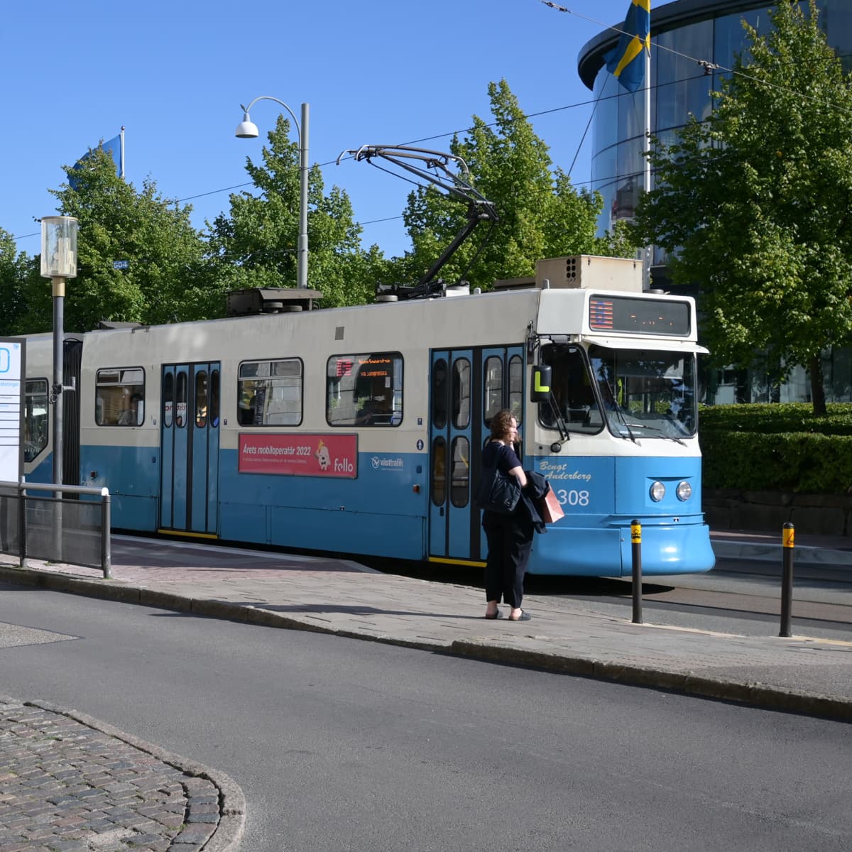 Ett blått och vitt tåg som passerar en hög byggnad.