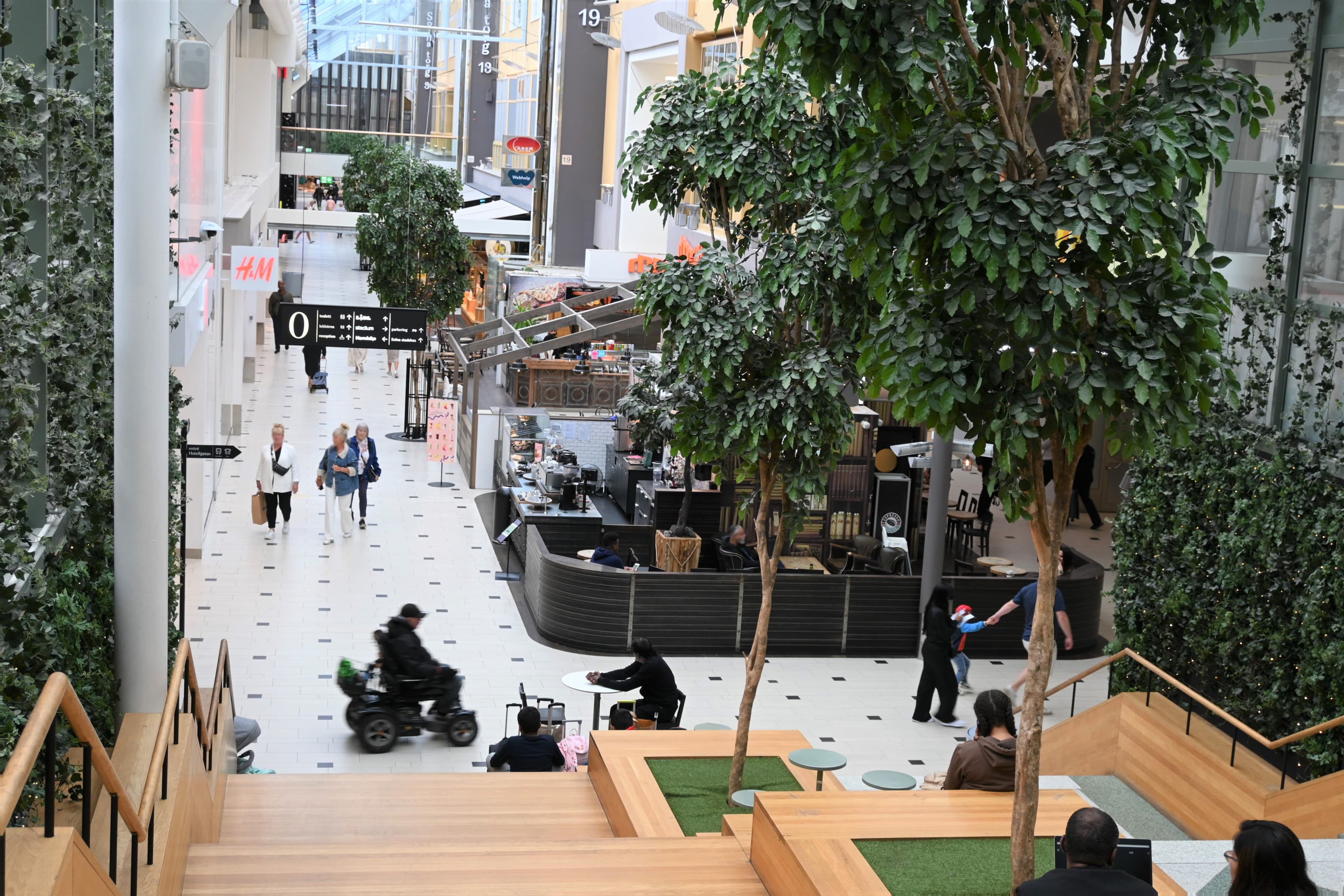 En grupp människor som sitter på bänkar i en byggnad.