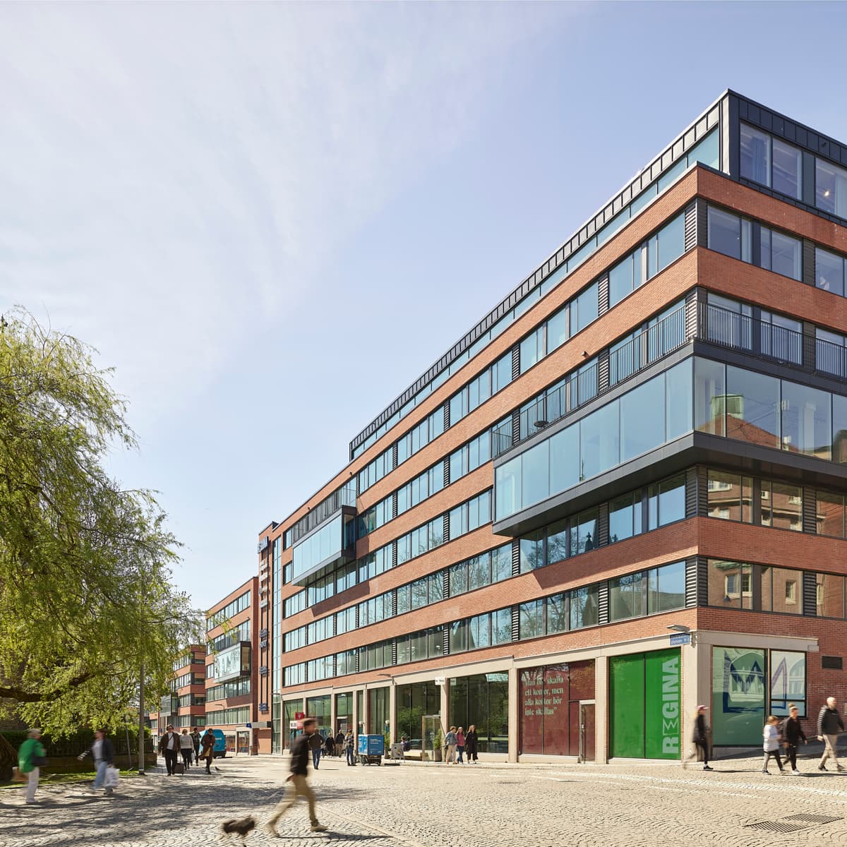 En grupp människor som går längs en gata bredvid en hög byggnad.