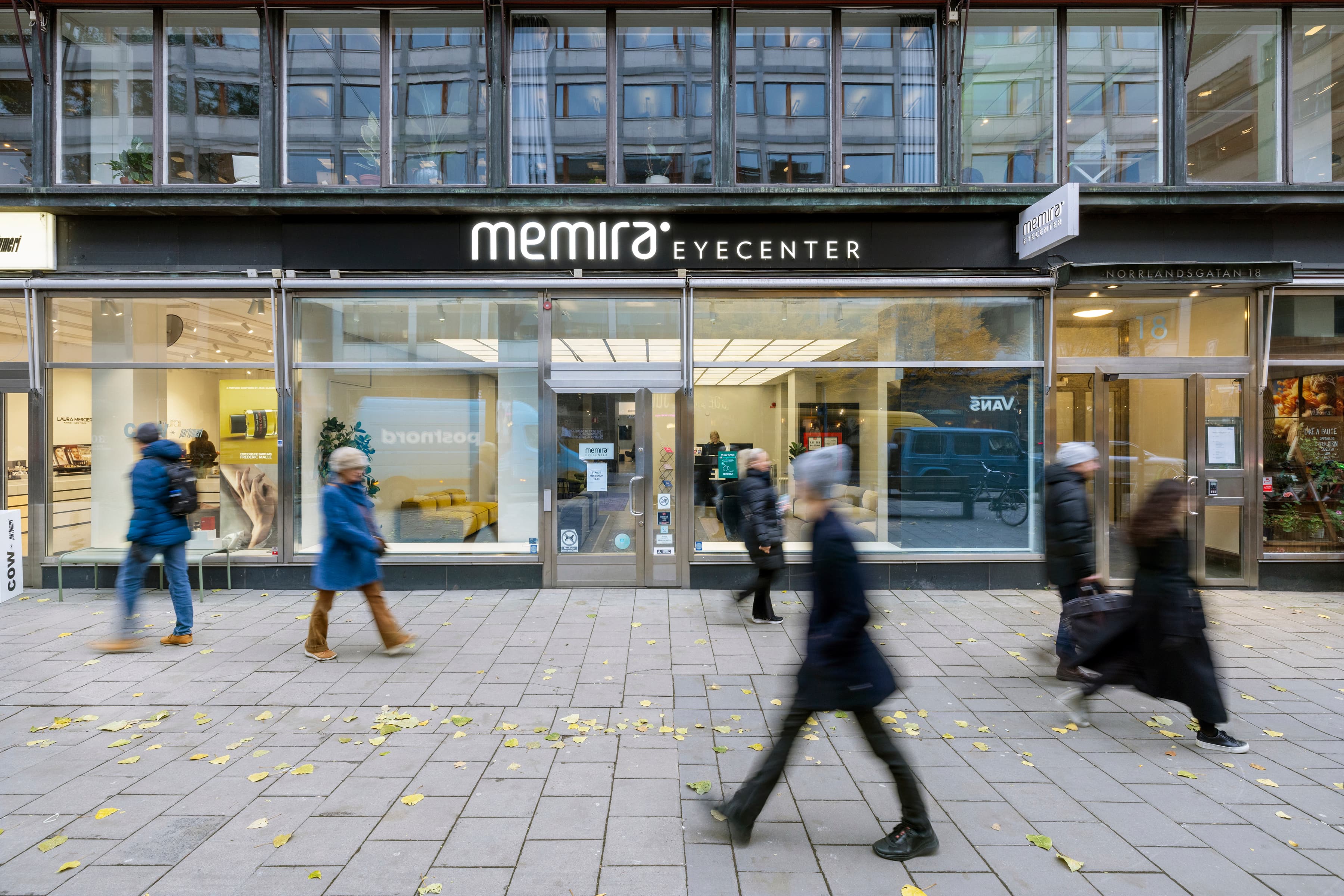 En grupp människor som går förbi en butiksfasad.