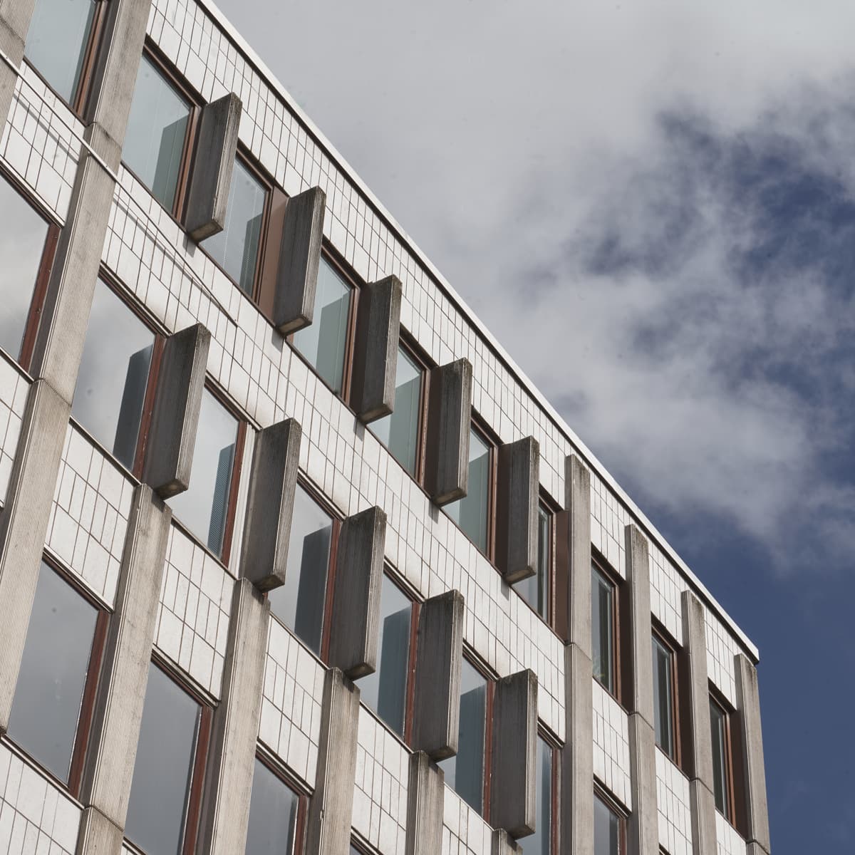 En hög byggnad med massor av fönster under en molnig blå himmel.