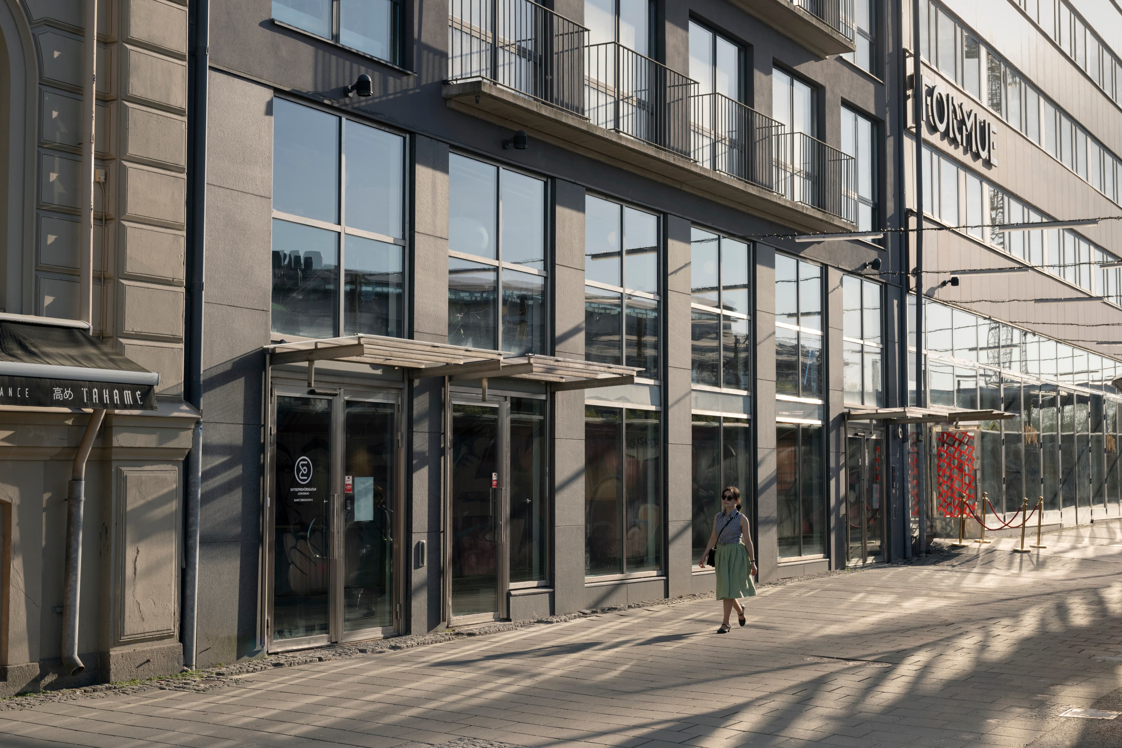 En person som går längs en gata bredvid en hög byggnad.