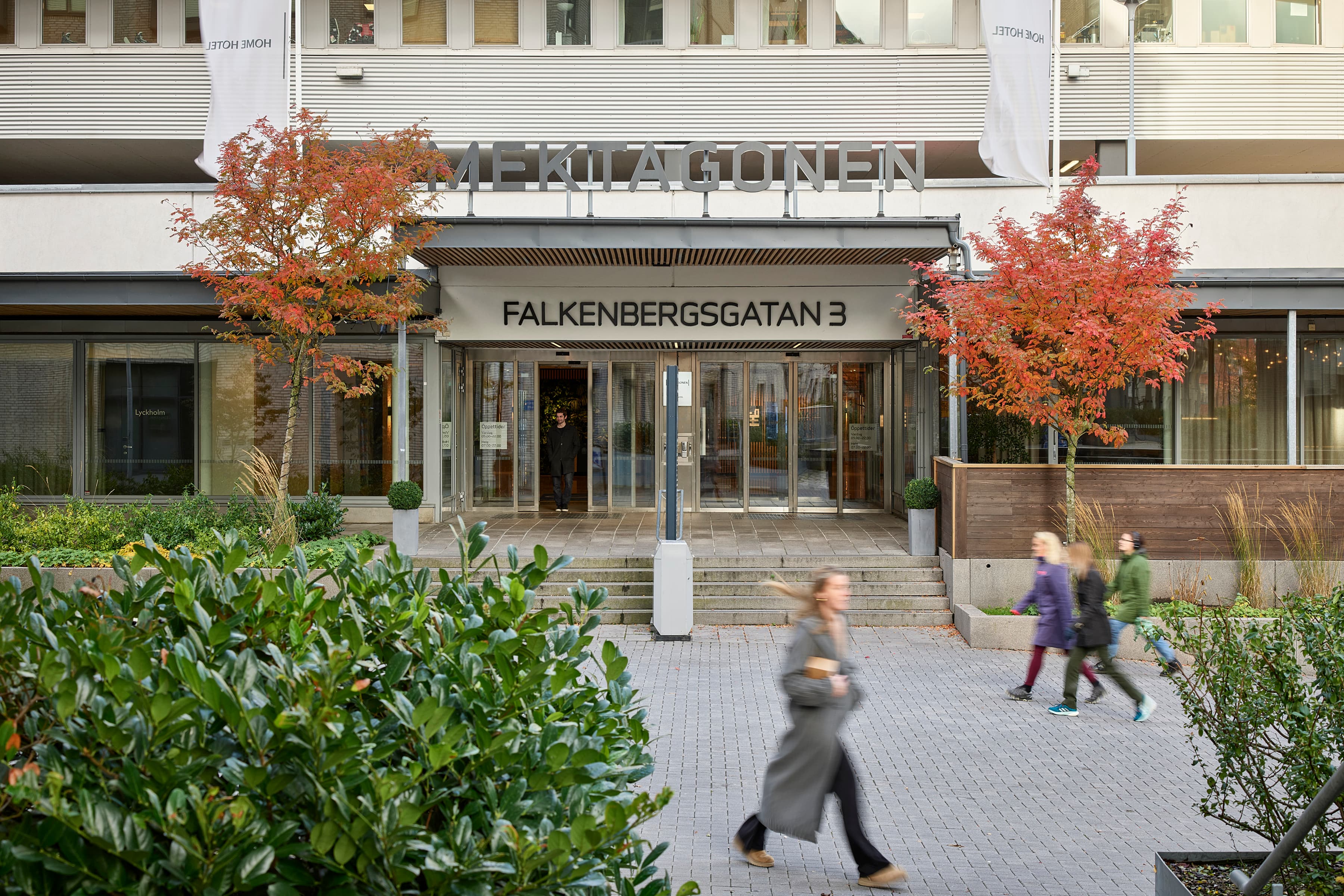 En grupp människor som går förbi en hög byggnad.