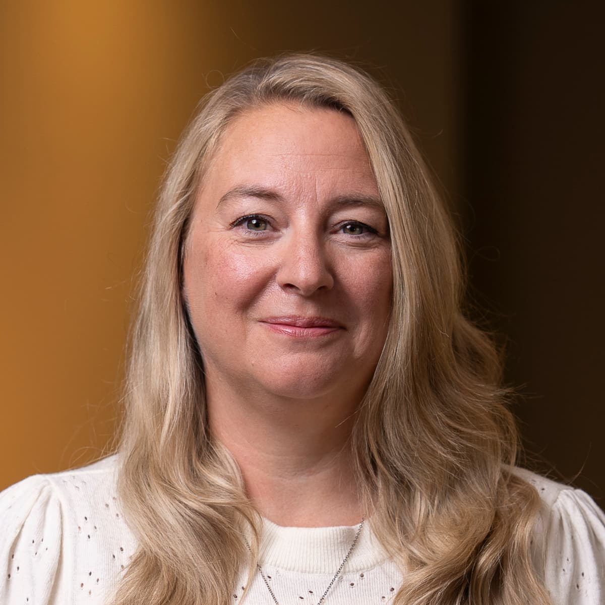 En kvinna som står i ett rum med en klocka på väggen.