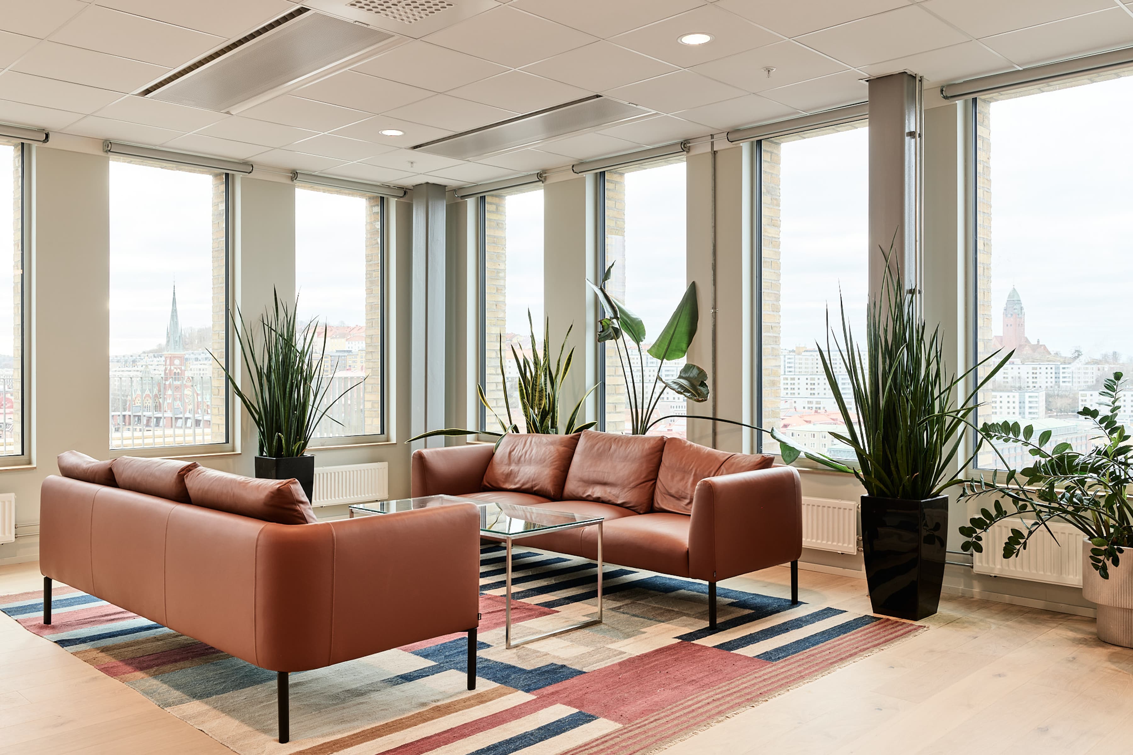 Ett vardagsrum fyllt med möbler och stora fönster.