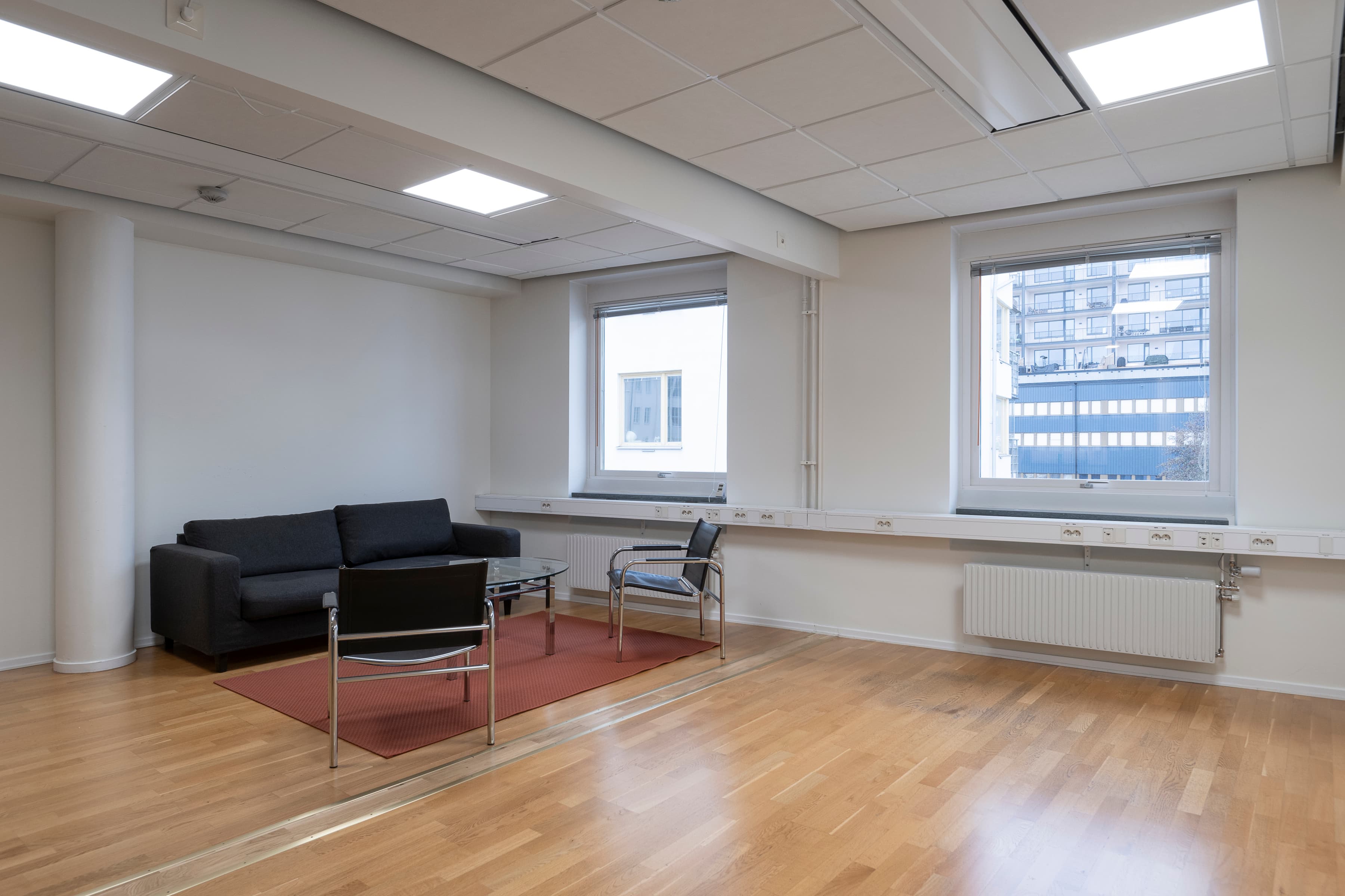 Ett tomt rum med en soffa, en stol och ett element.