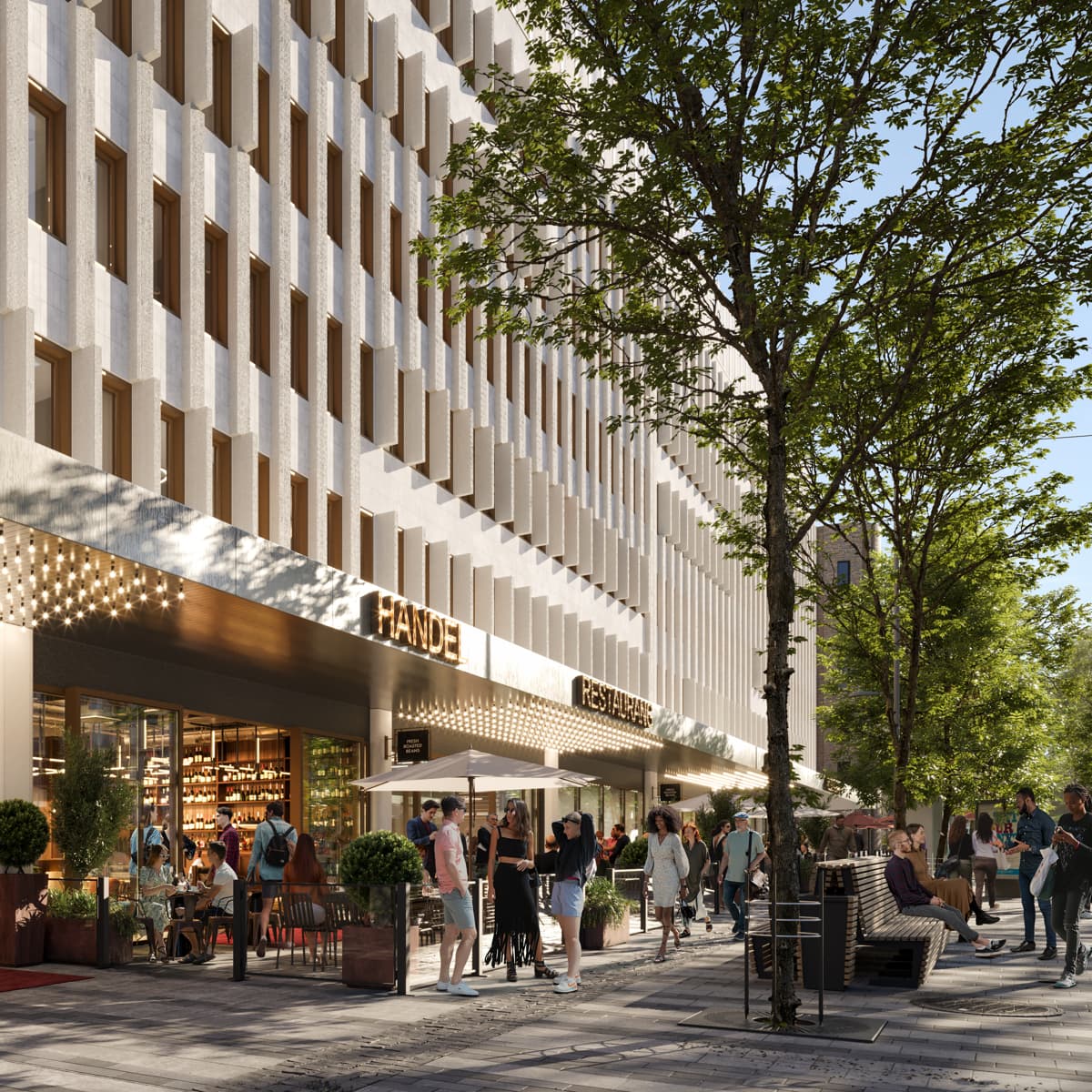 En grupp människor som går längs en gata bredvid en hög byggnad.