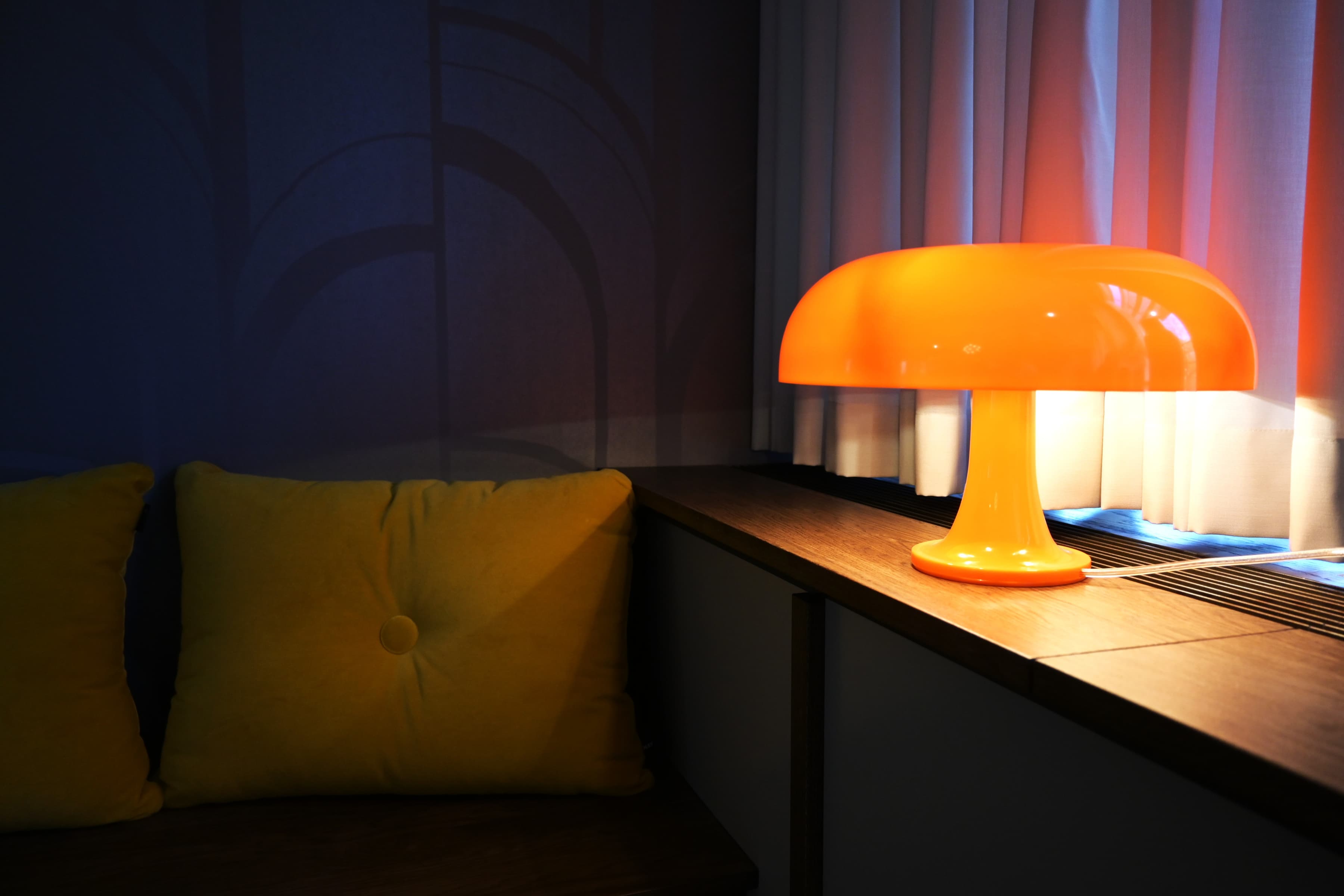 En gul lampa som sitter på ett träbord.