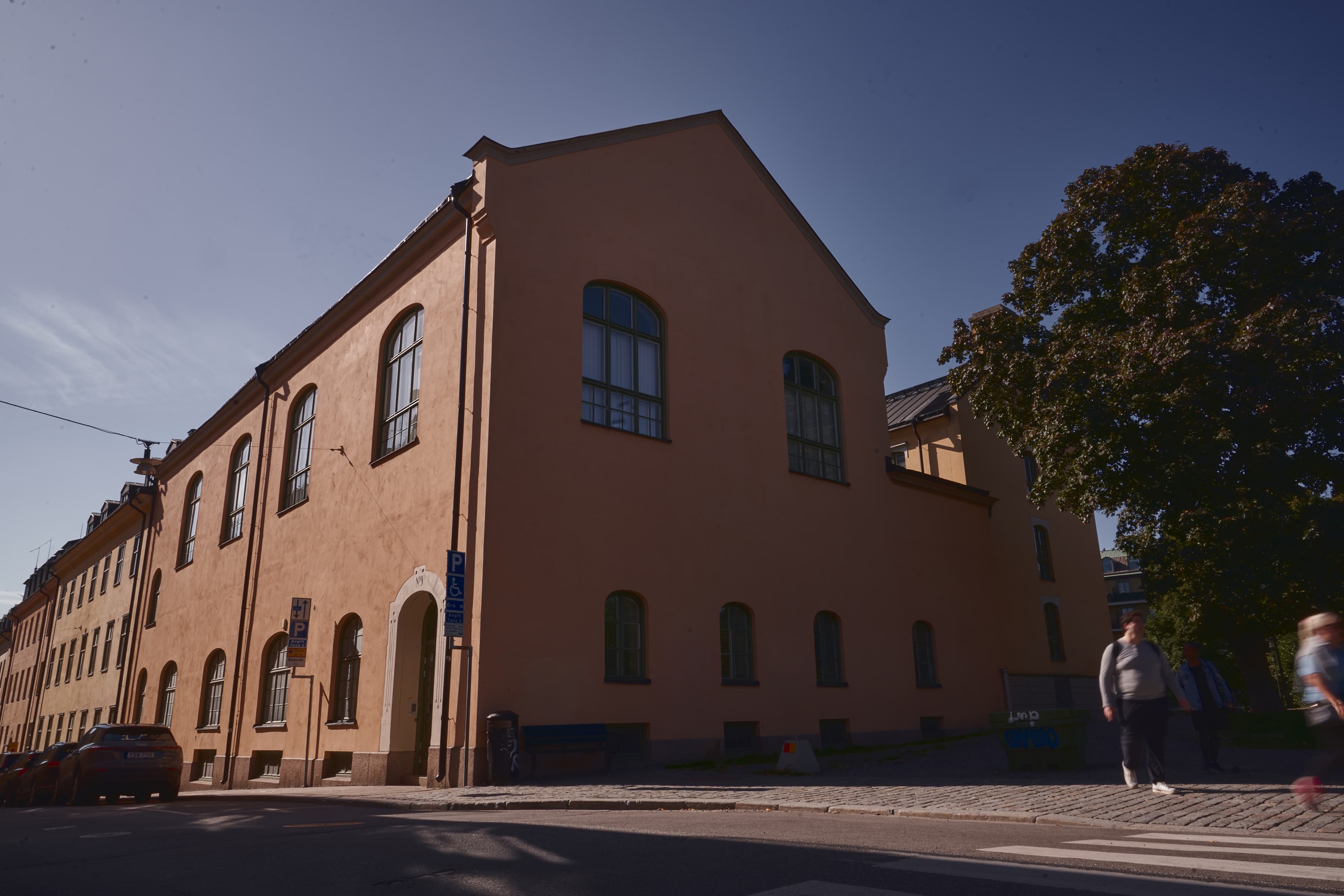 Två personer går längs gatan framför en byggnad.