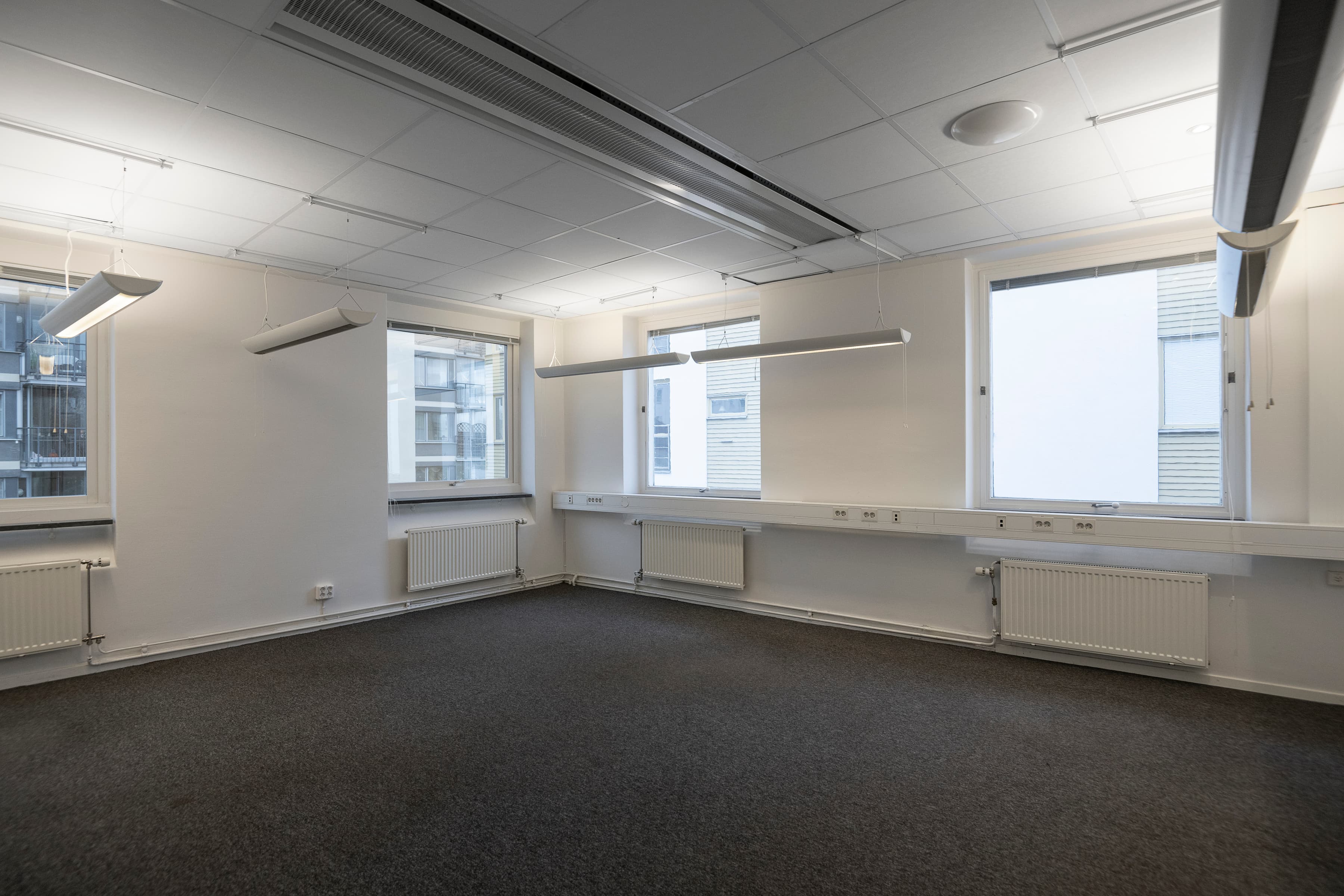 Ett tomt rum med fönster och en radiator.