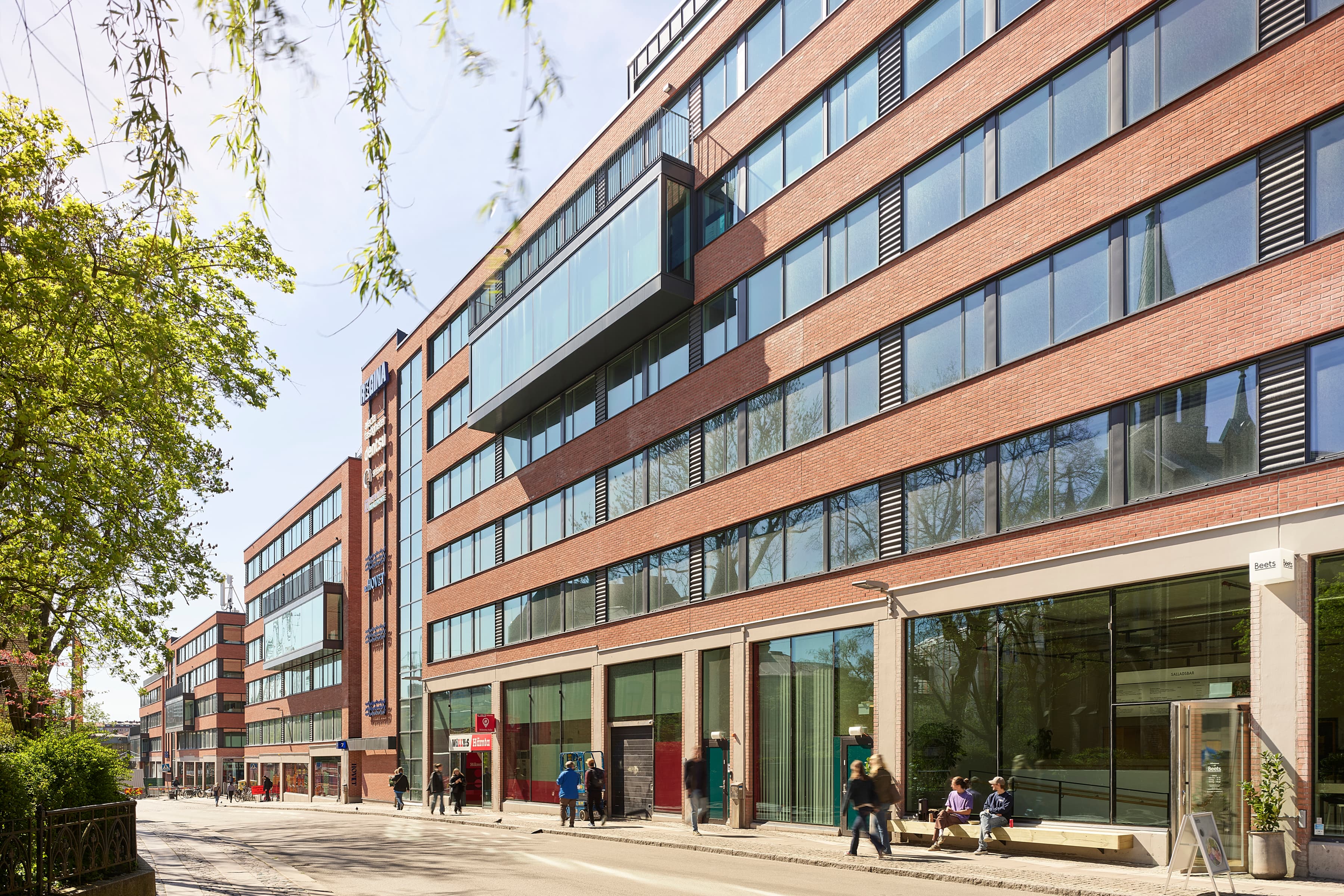 En grupp människor som går längs en gata bredvid en hög byggnad.