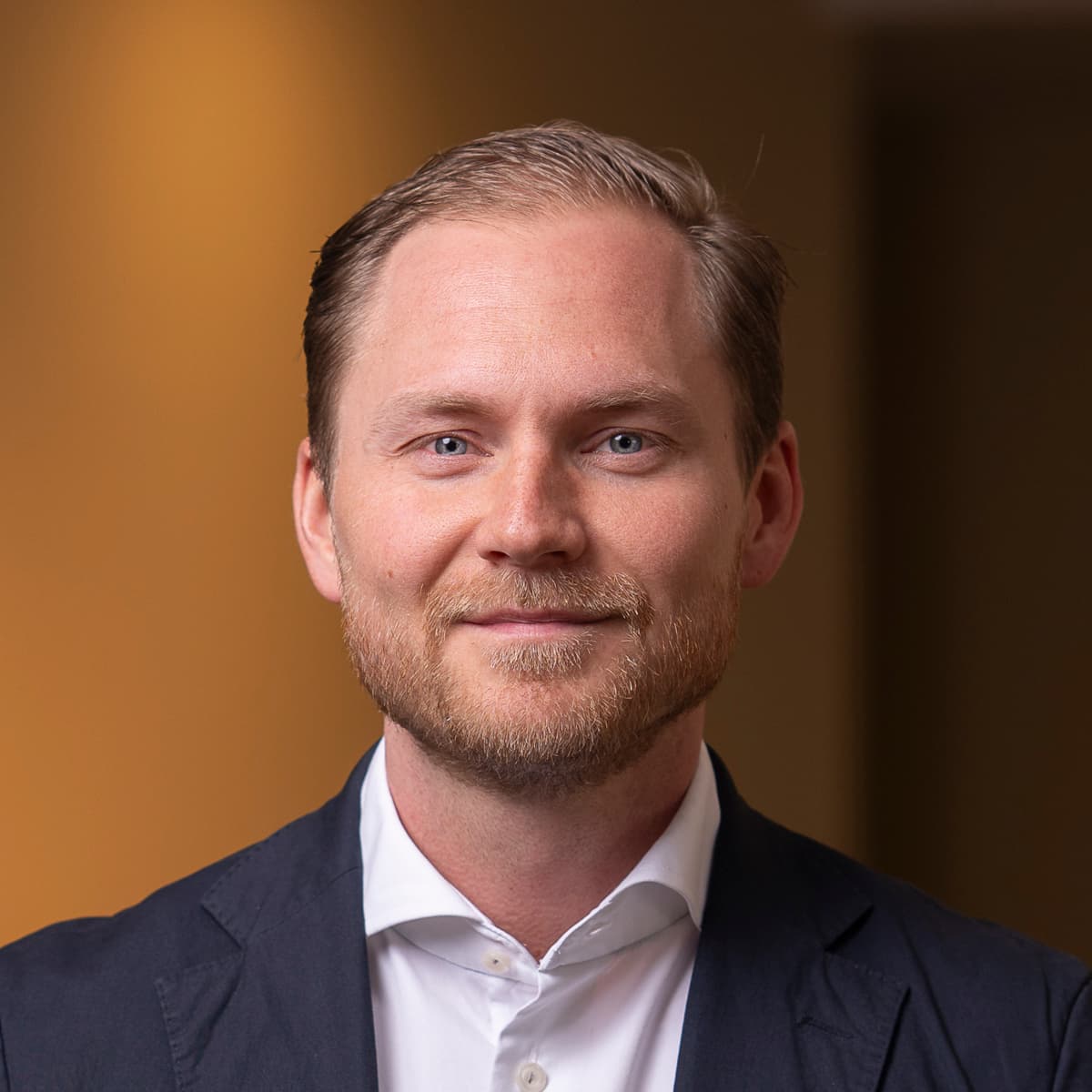 En kostymklädd man står i ett rum.