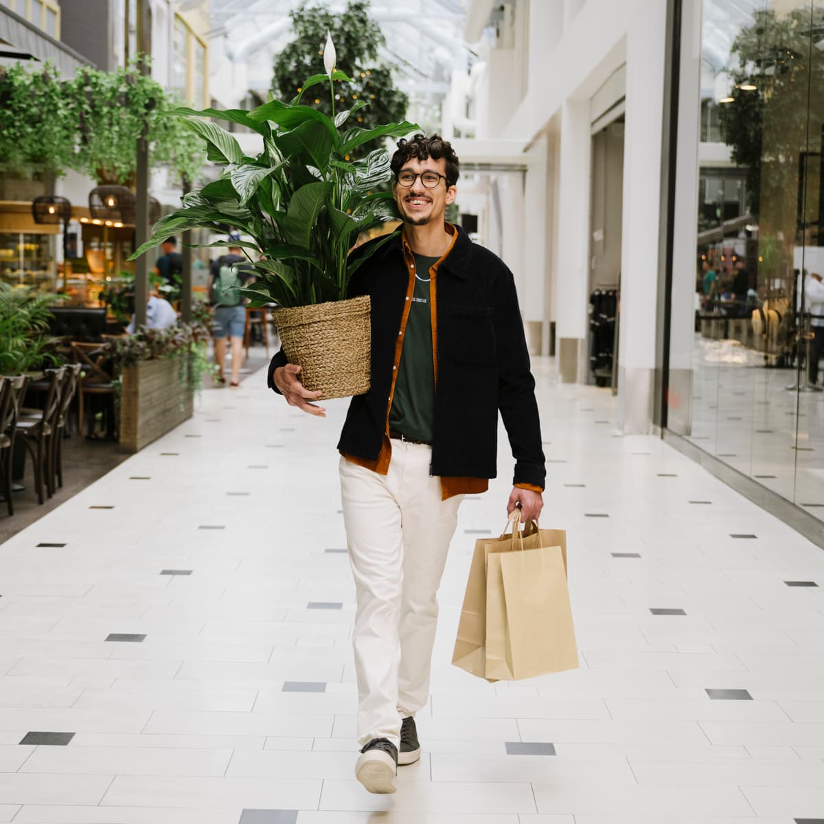 En man som går i ett shoppingcenter med shoppingkassar.