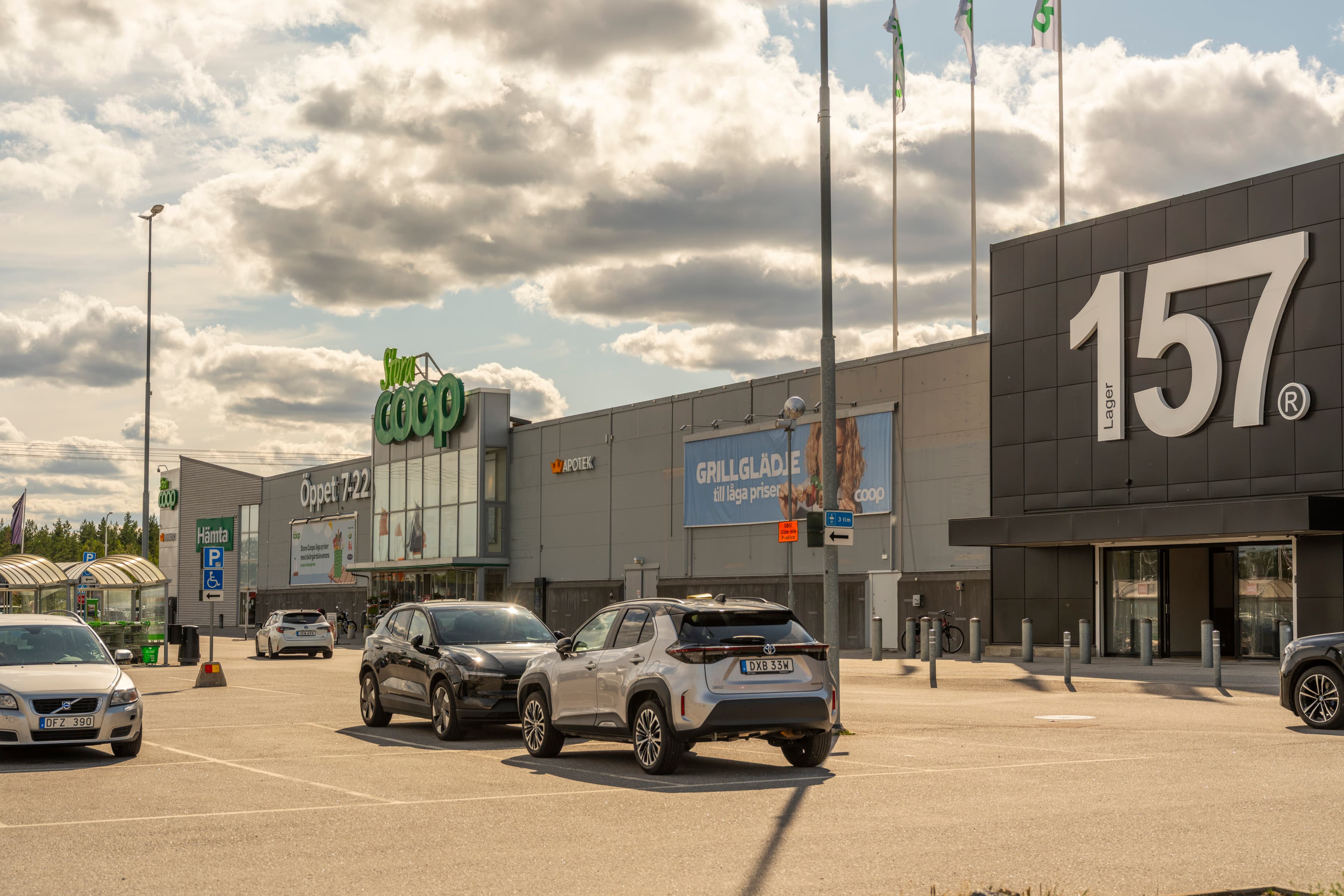 Flera bilar som står parkerade på en parkeringsplats framför en byggnad.
