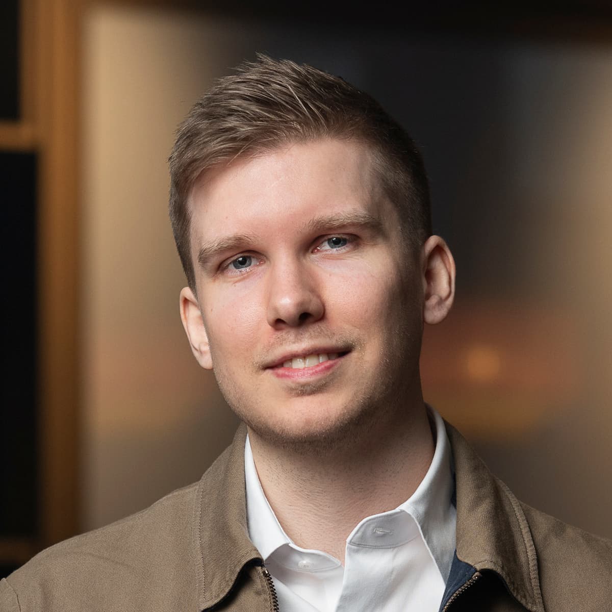 En man som står i ett rum bredvid en lampa.