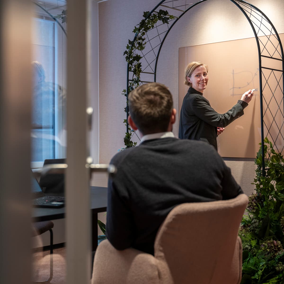 En man står framför en spegel och pratar med en annan man.