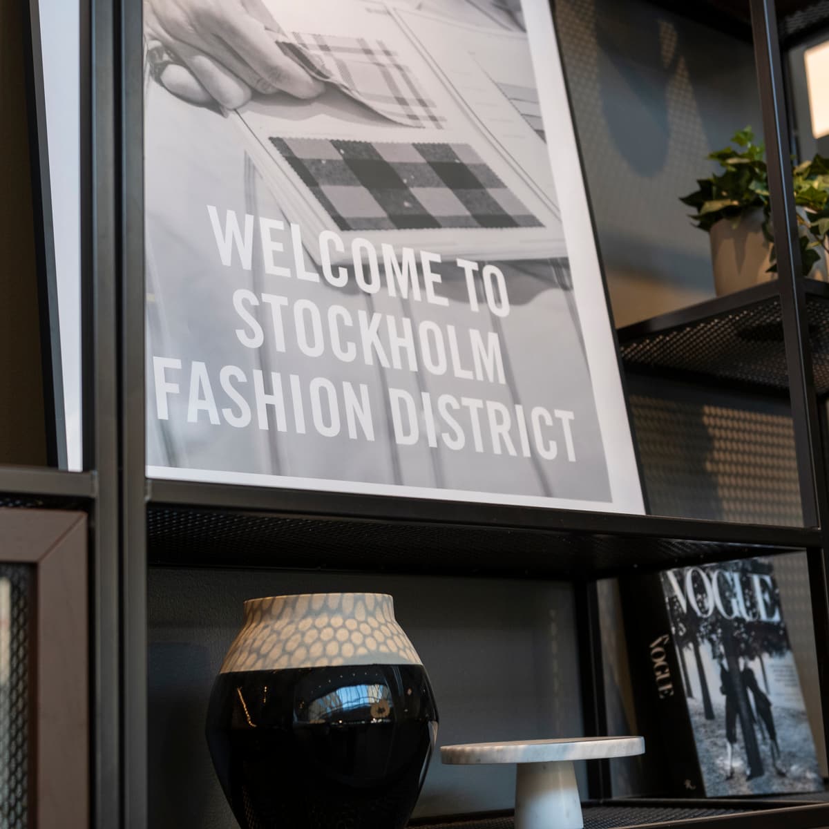 En svart vas som står på en trähylla.