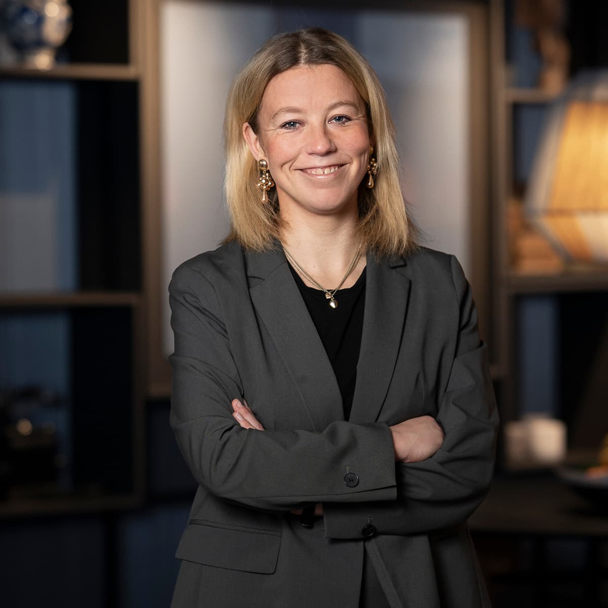 En kvinna i affärskostym står framför ett bord.