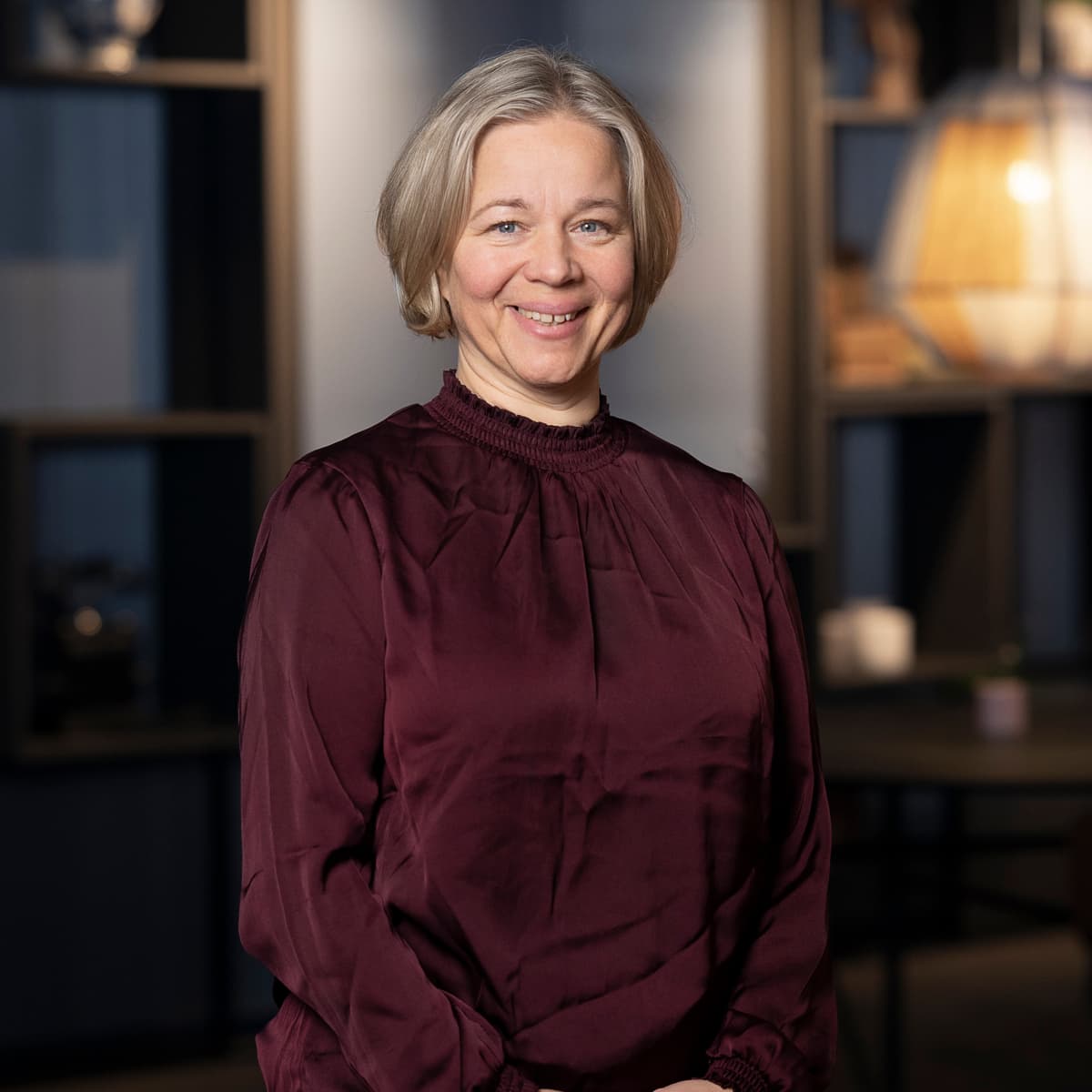 En kvinna står framför ett bord i ett rum.