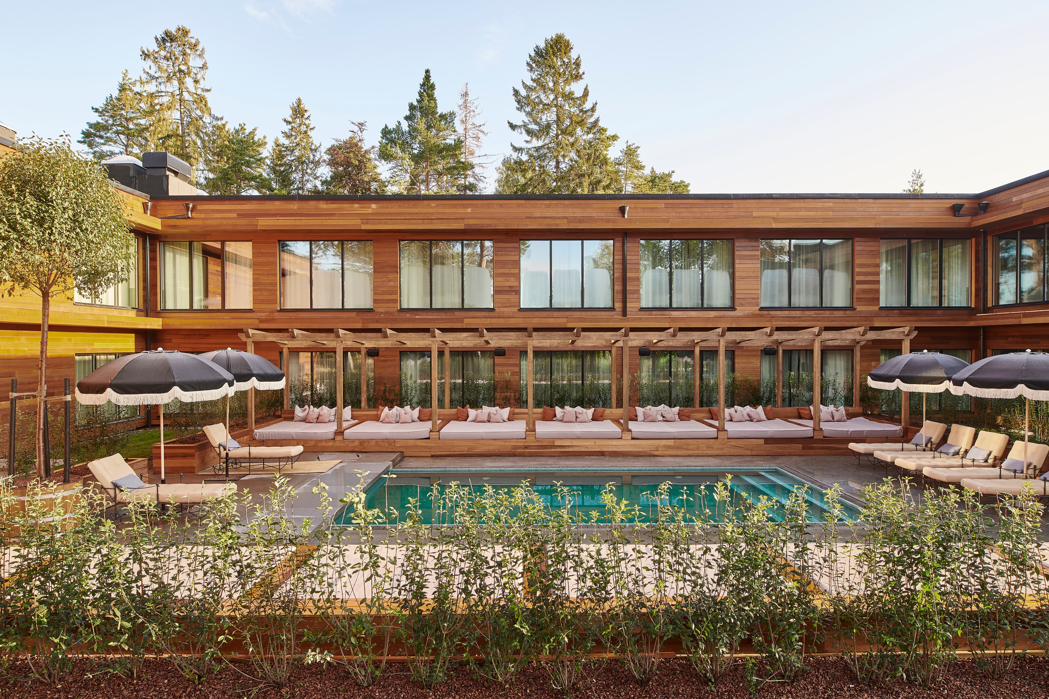 Ett hus med en pool omgiven av solstolar på gräsmattan.