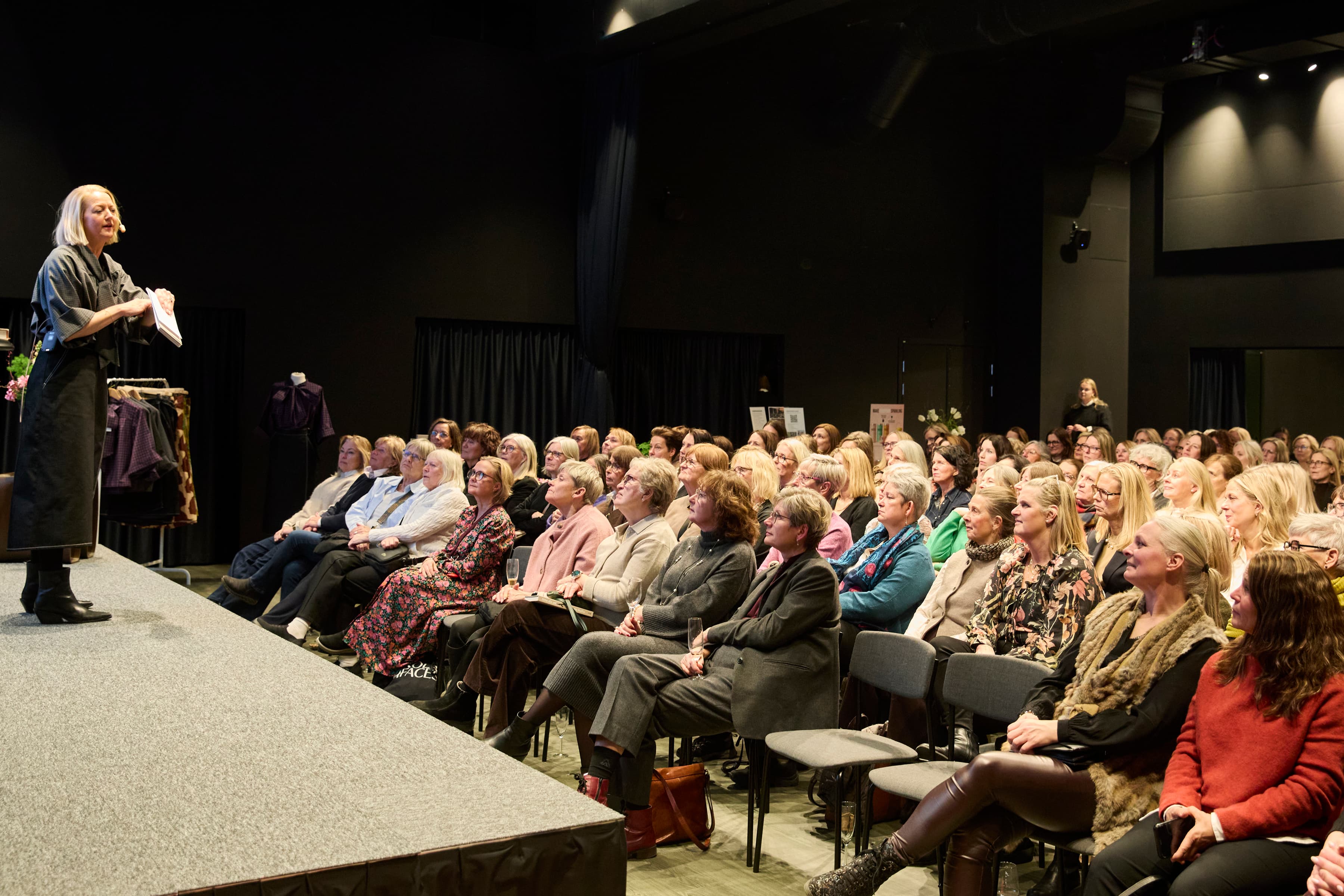 En kvinna som står på ett podium framför en folkmassa.