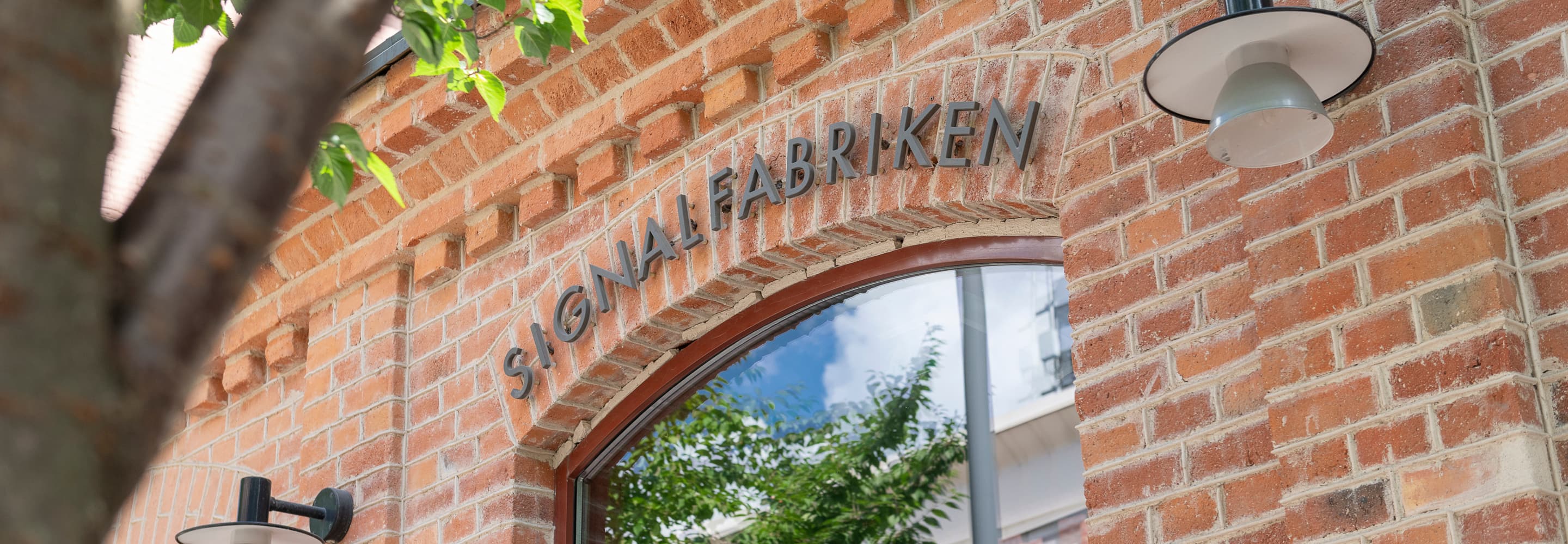 En tegelbyggnad med ett träd framför.