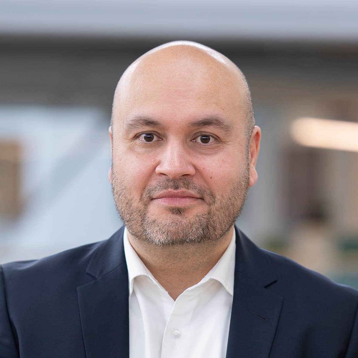 En man i kostym och slips lutar sig mot ett räcke.