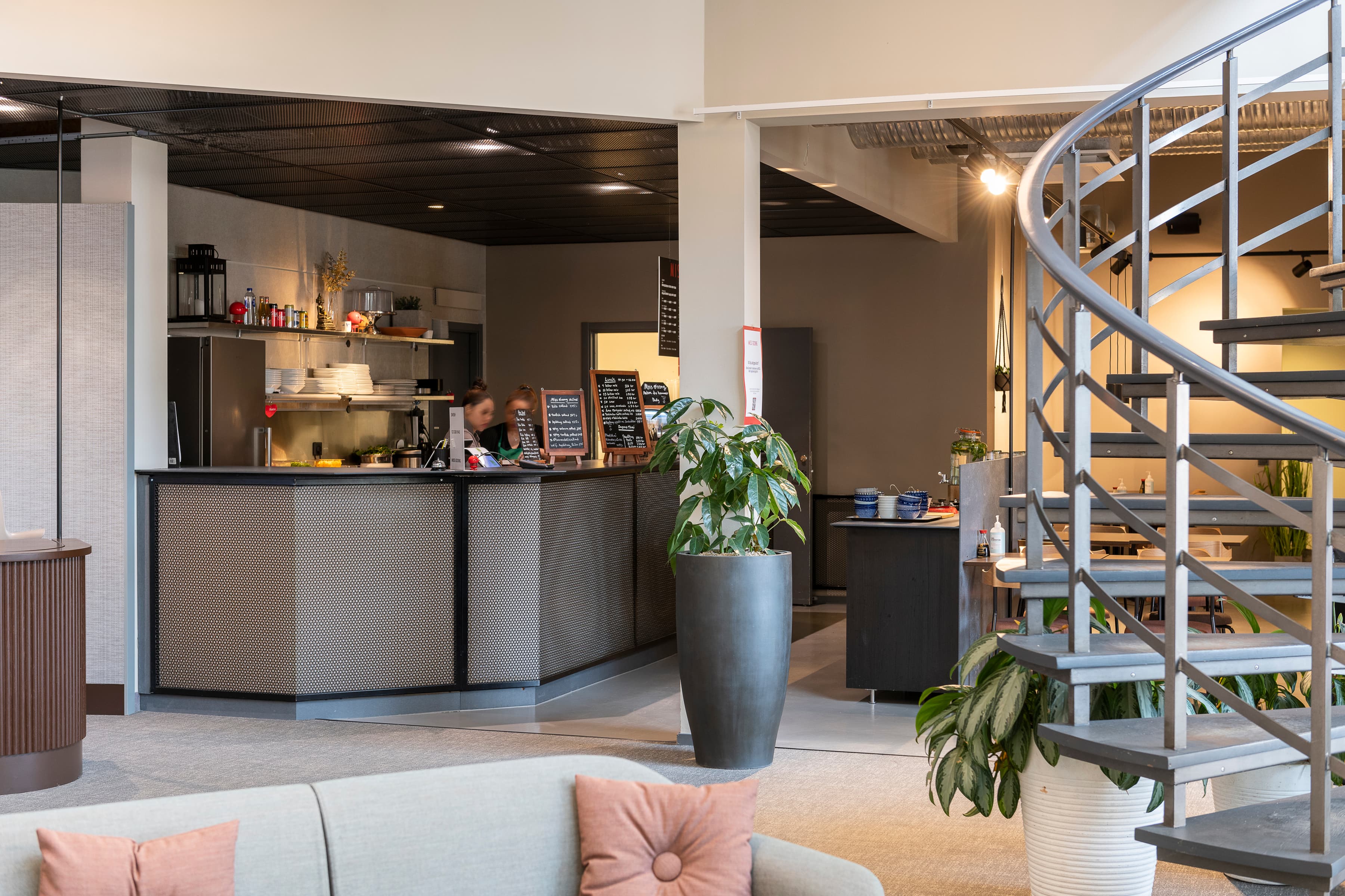 Ett vardagsrum med en spiraltrappa bredvid en bar.