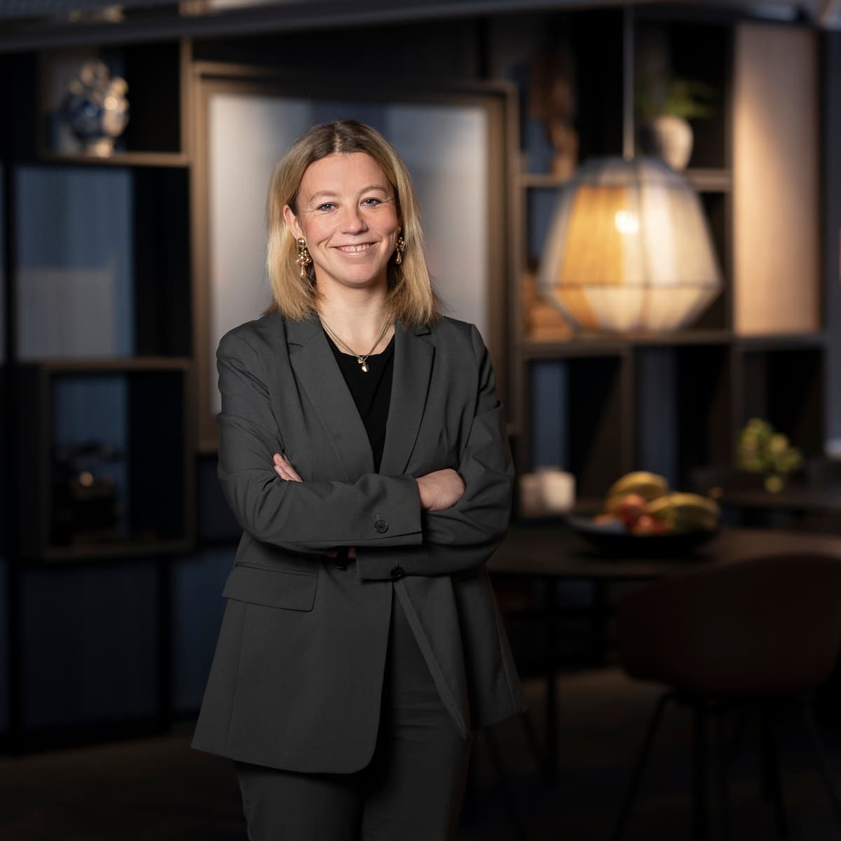 En kvinna i affärskostym står framför ett bord.