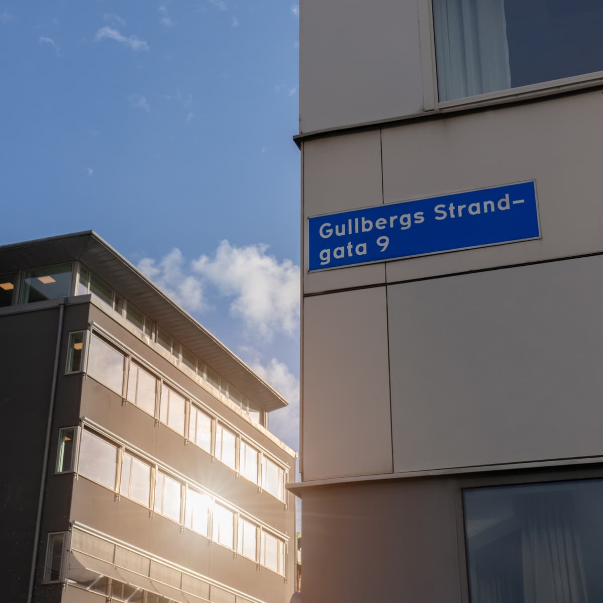 En hög byggnad med en blå gatuskylt på sidan.