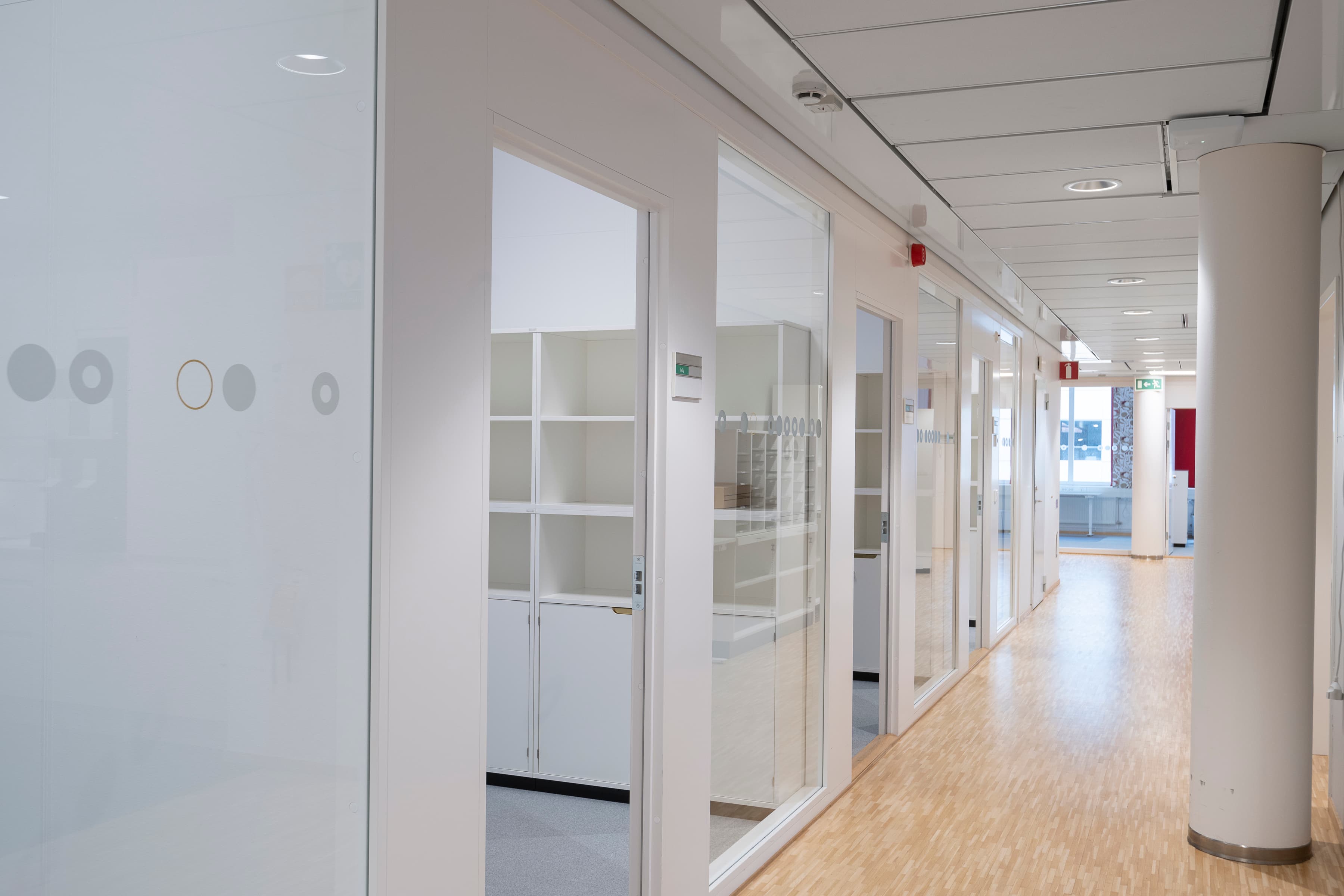 En lång korridor med vita väggar och trägolv.