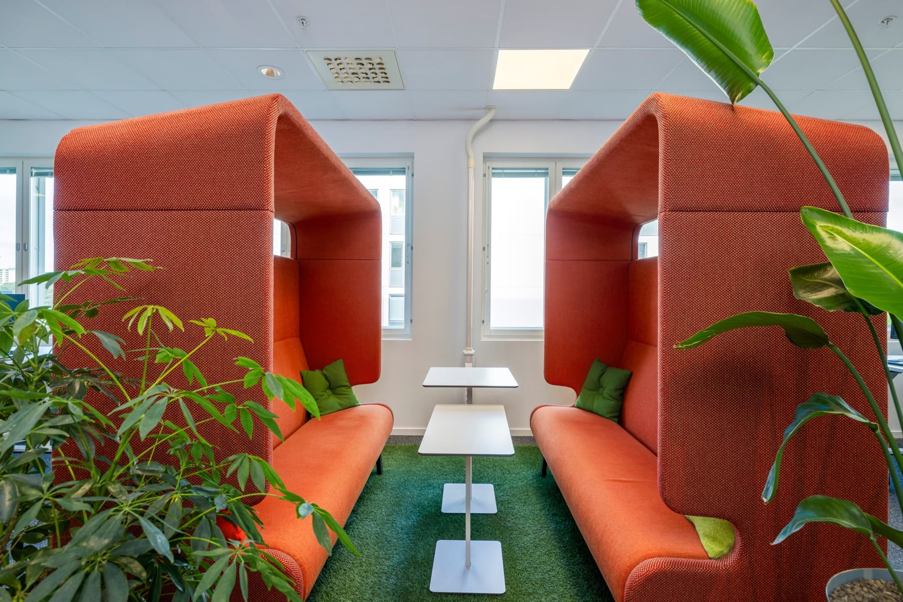 Ett vardagsrum med orangea soffor och gröna växter.