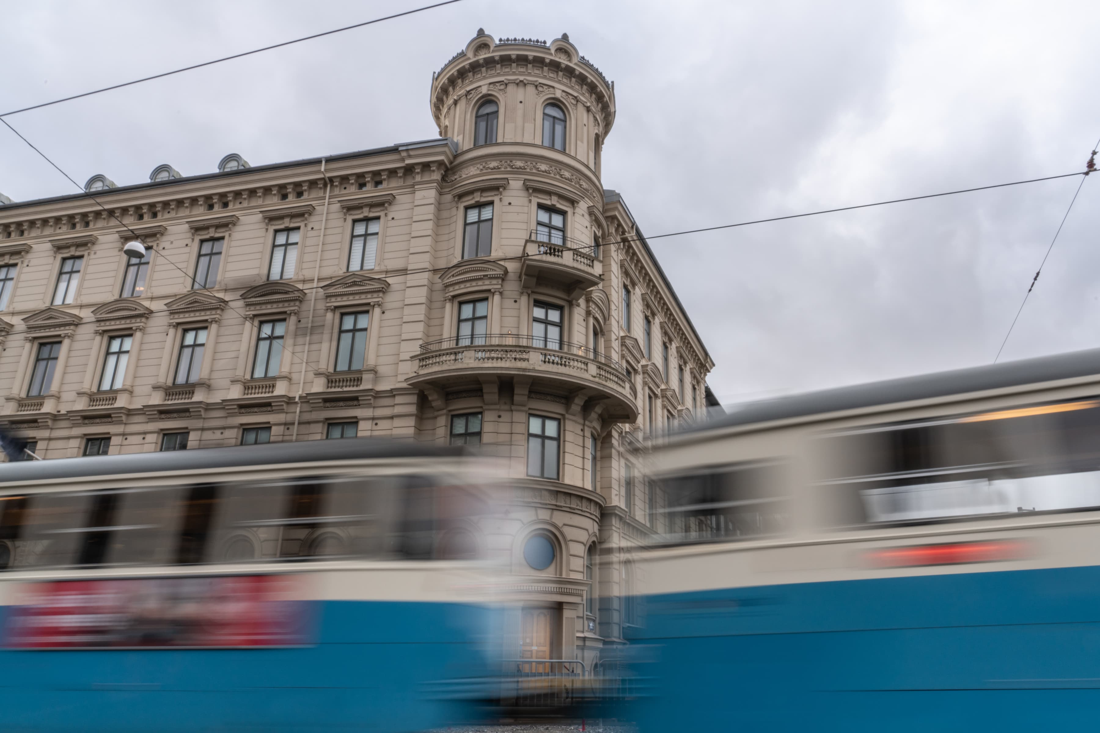 Ett suddigt foto av ett tåg som passerar förbi en byggnad.