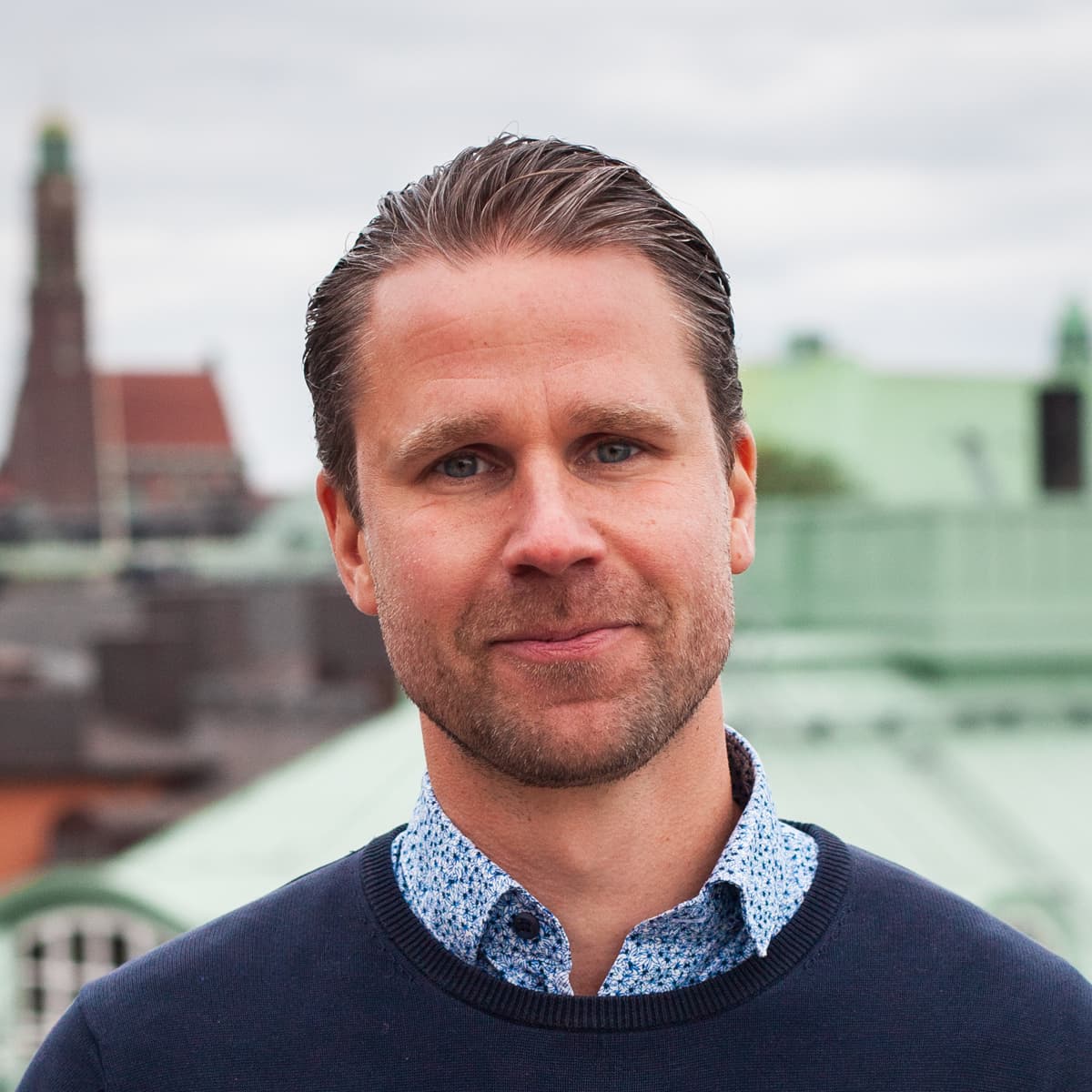 En man i blå tröja står på en balkong.