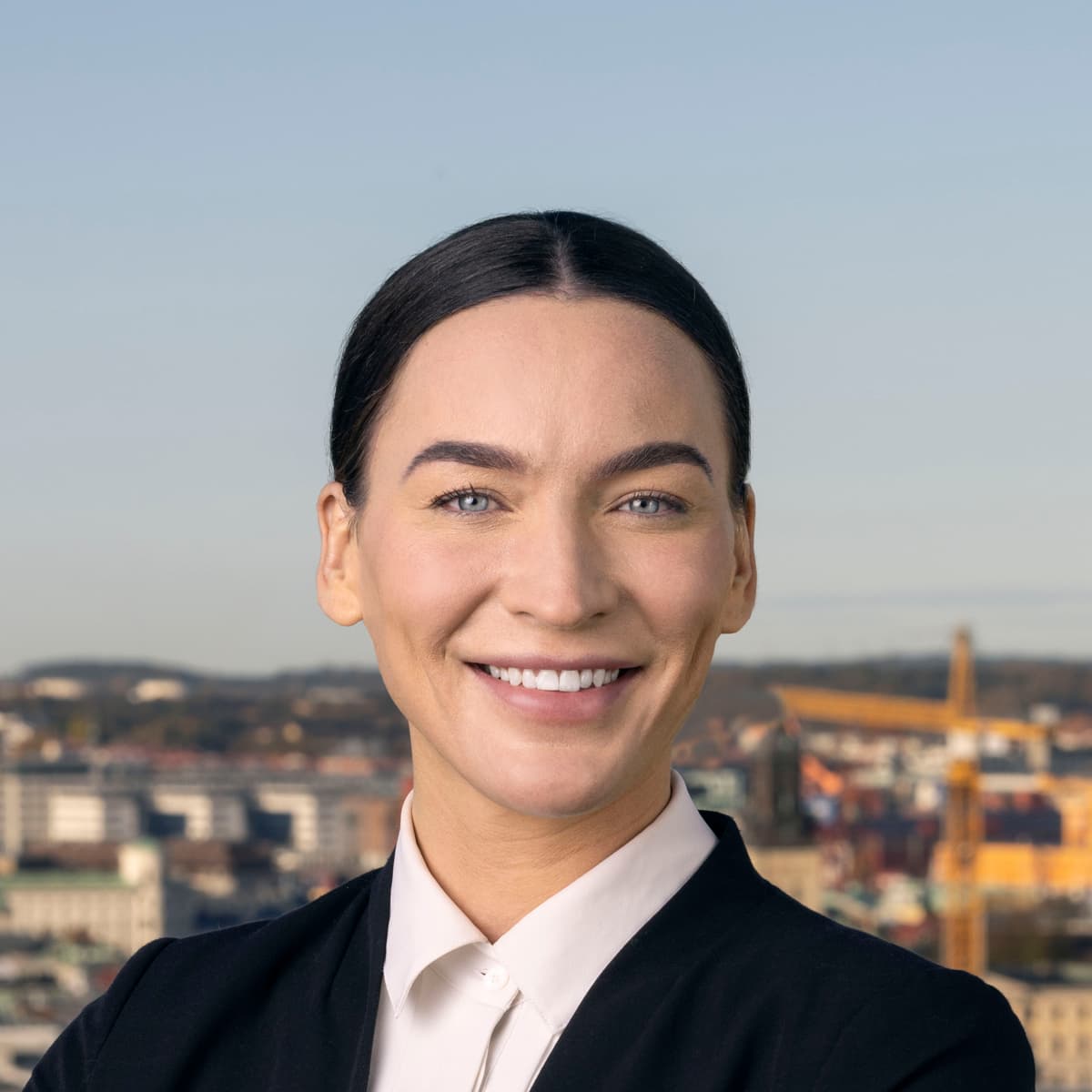 En kvinna med armarna i kors står framför en stad.