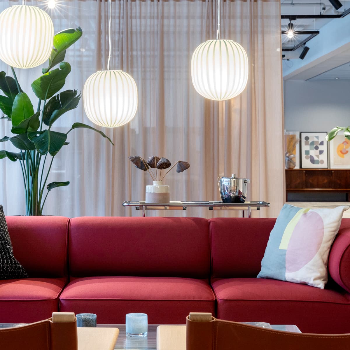 En röd soffa som sitter i ett vardagsrum bredvid ett bord.