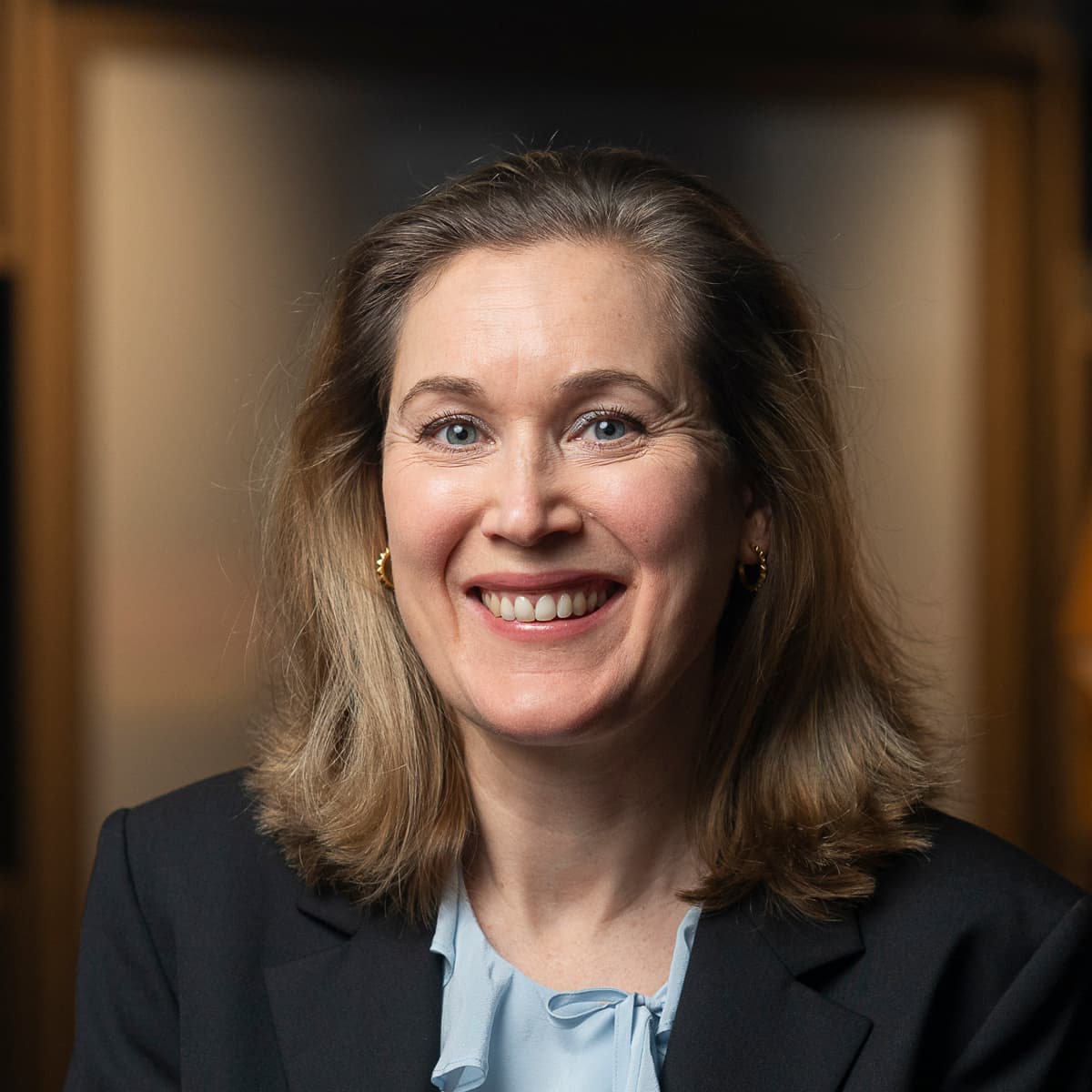 En kvinna i svart jacka står i ett rum.