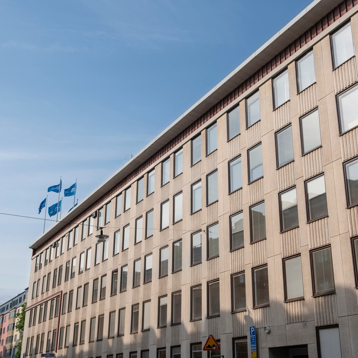 En hög byggnad med många fönster intill en gata.