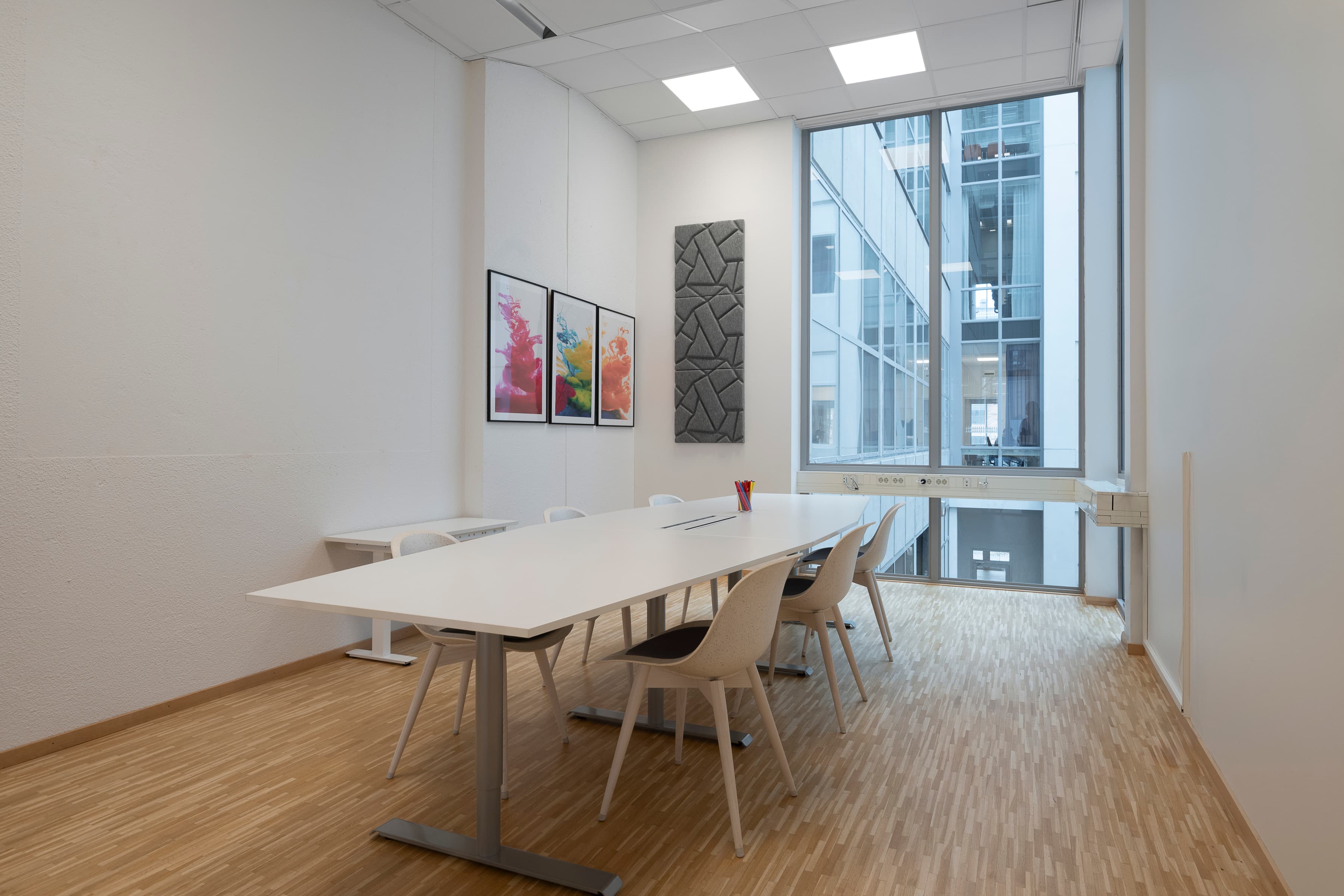 Ett konferensrum med bord, stolar och ett stort fönster.