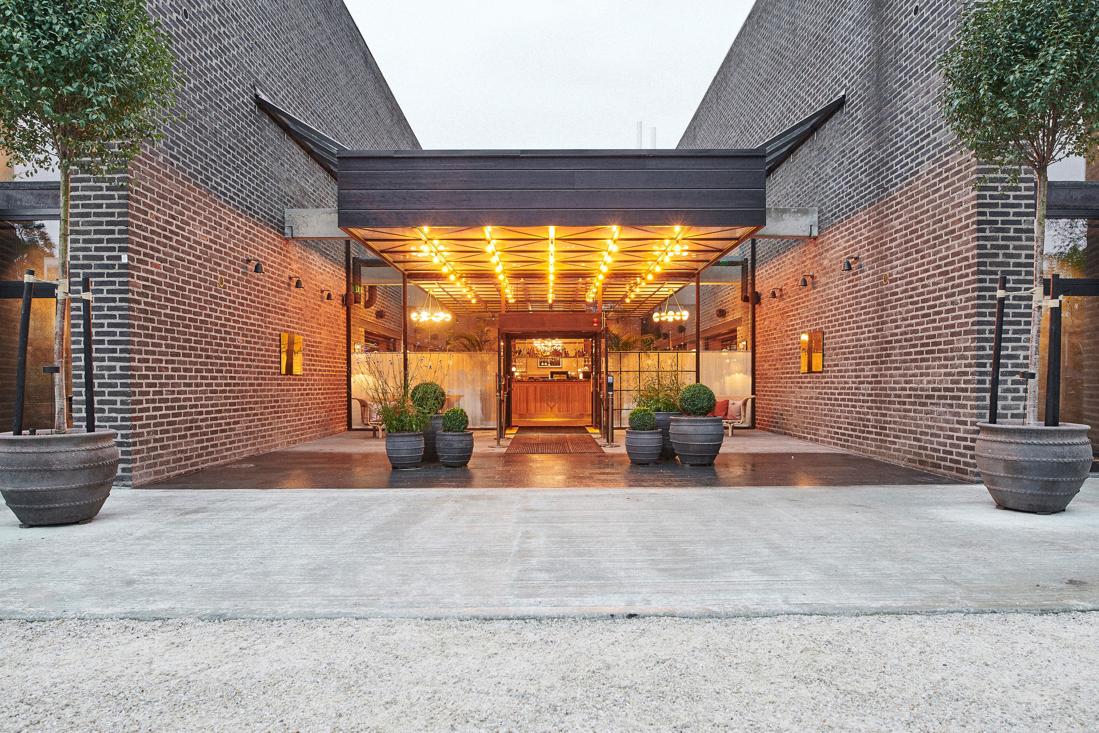 En stor tegelbyggnad med två stora planteringar framför.