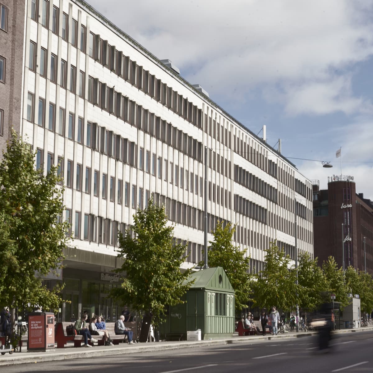 En bil som kör längs en gata bredvid en hög byggnad.