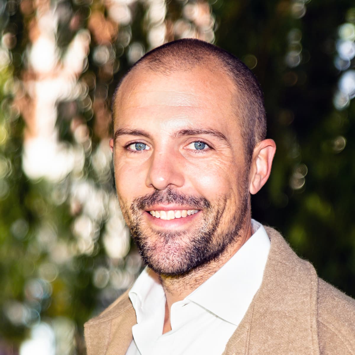 En man med bockskägg ler mot kameran.