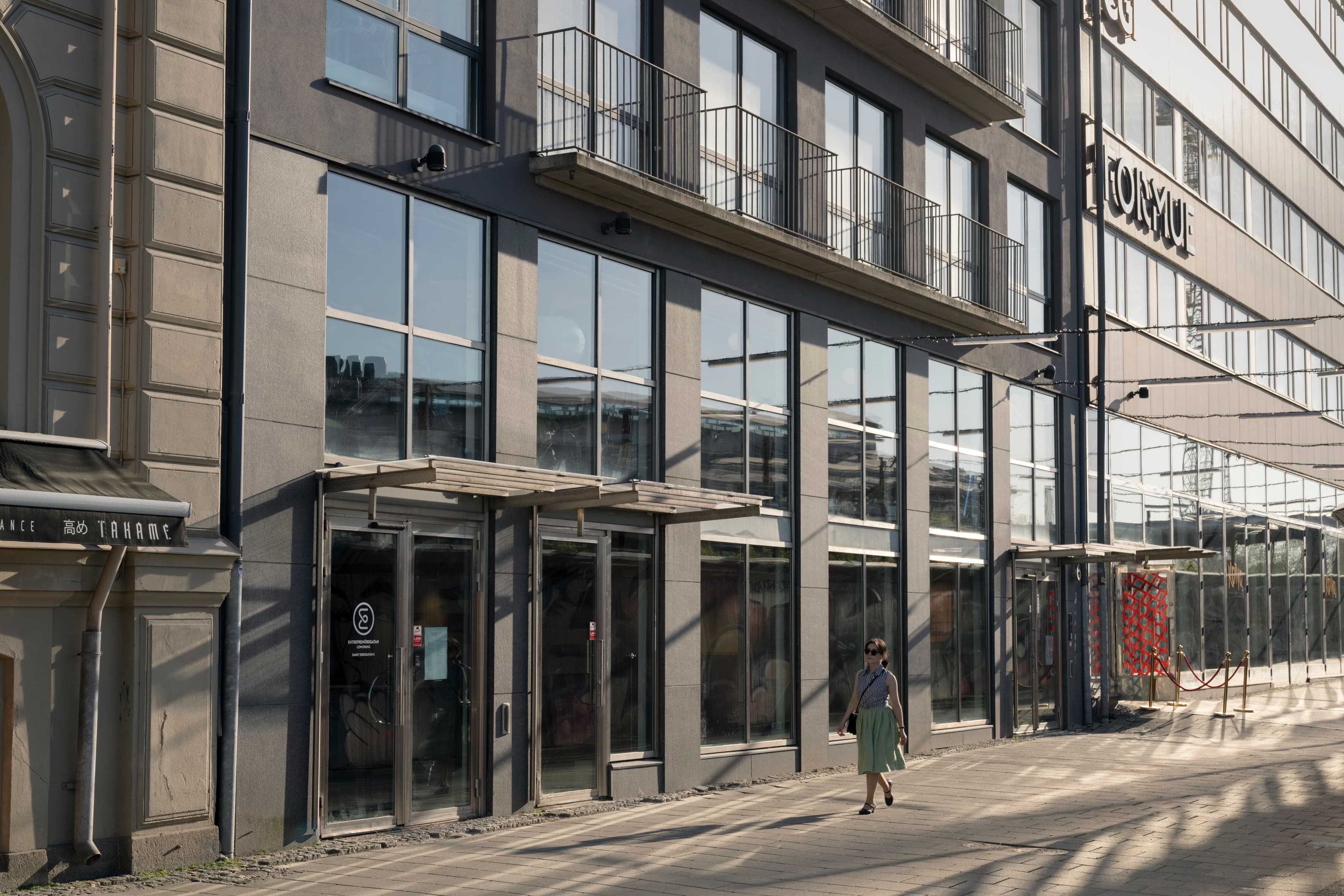 En person som går längs en gata bredvid en hög byggnad.