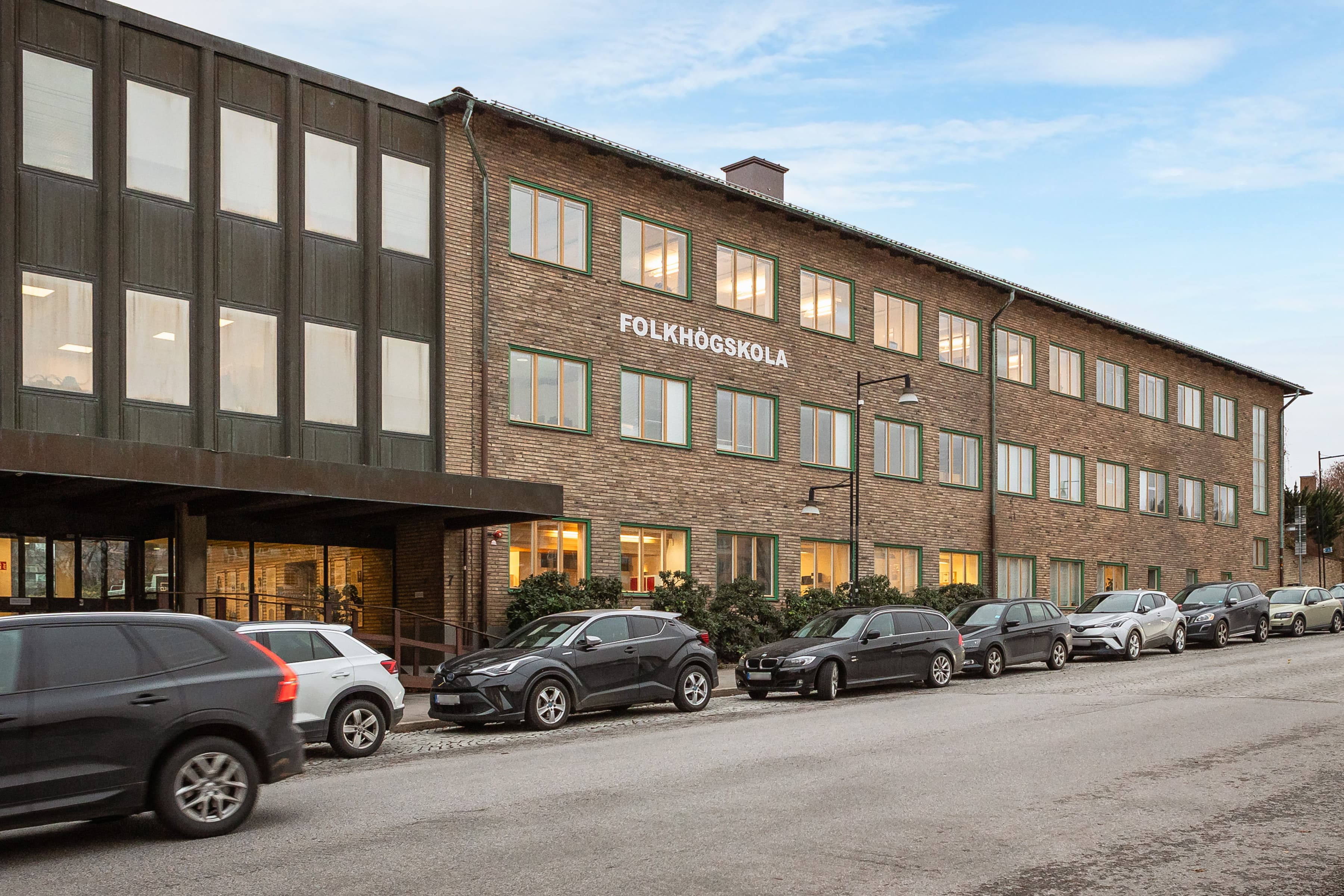 En rad bilar parkerade framför en byggnad.