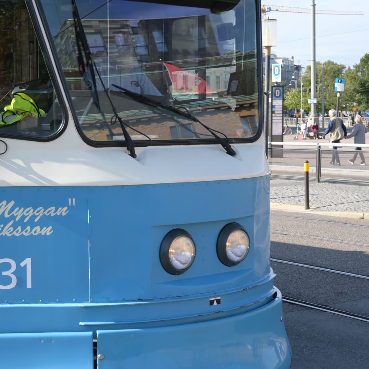 En blå och vit spårvagn kör längs en gata.